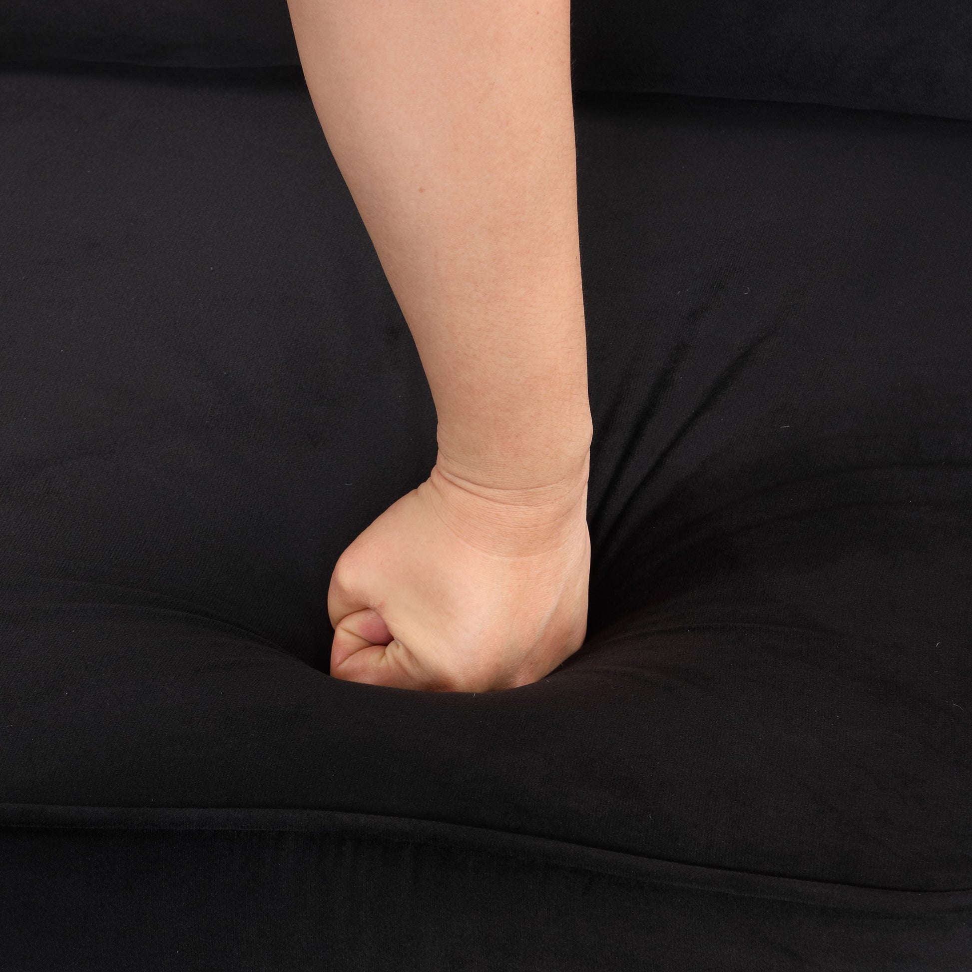 Black velvet fabric pillow hand pressing into soft material