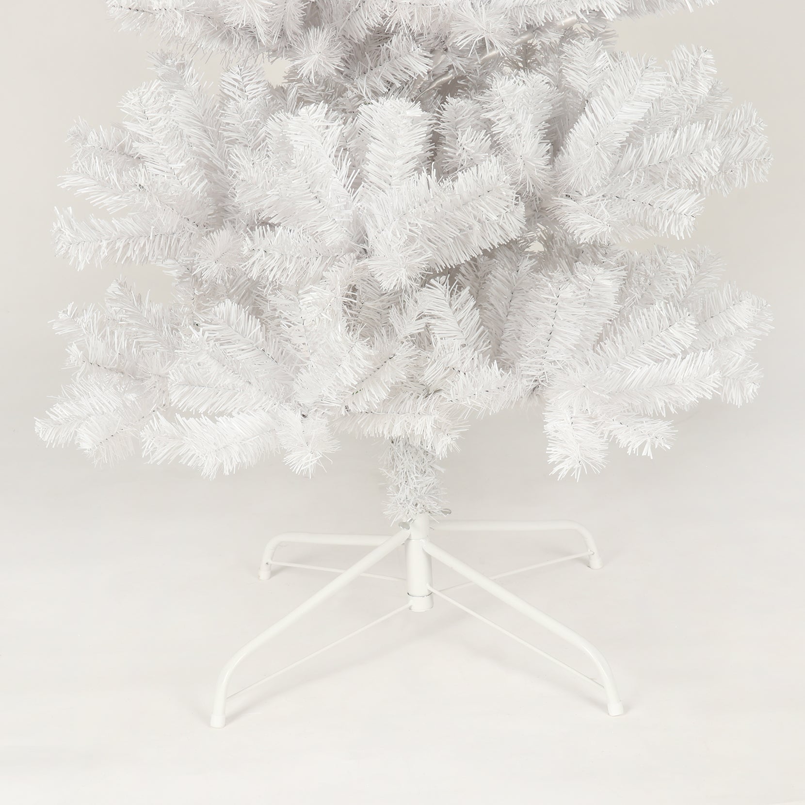 Close up of a fluffy white artificial Christmas tree with a metal stand