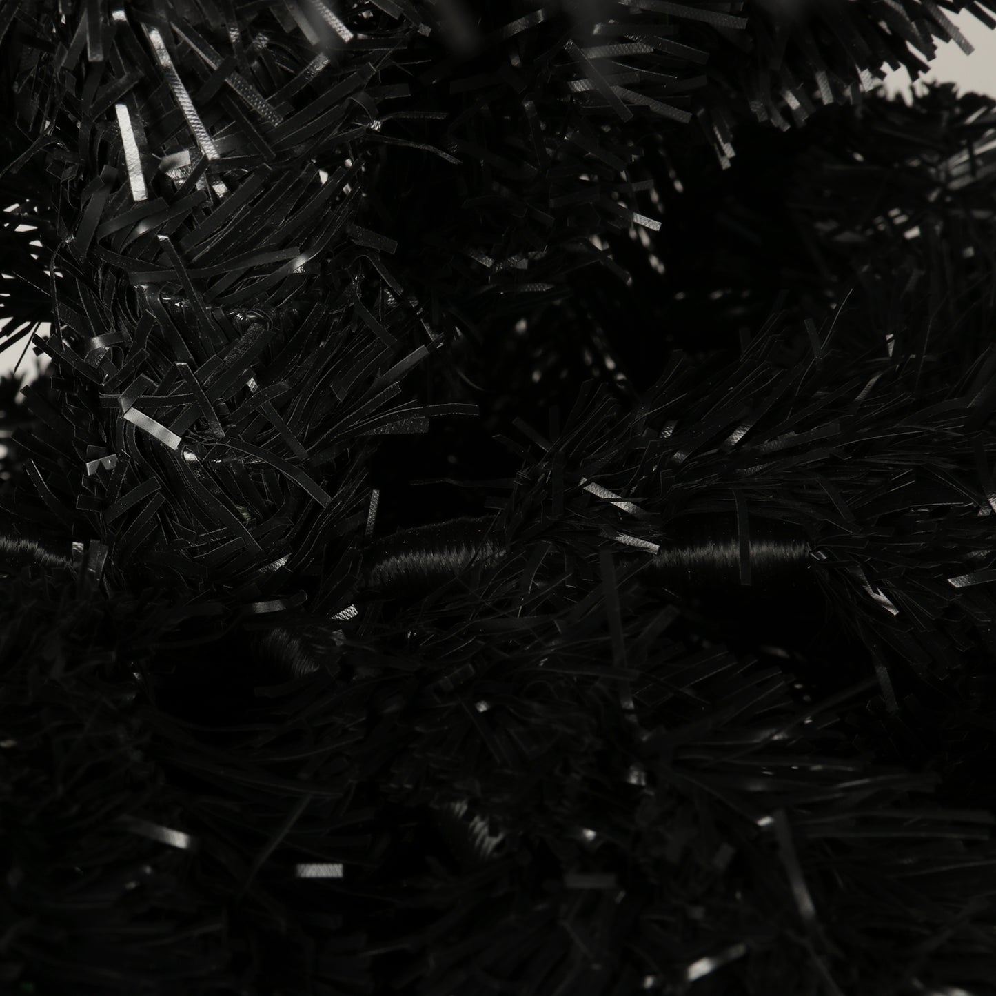 Closeup of dense black artificial Christmas tree branches with a slightly glossy finish