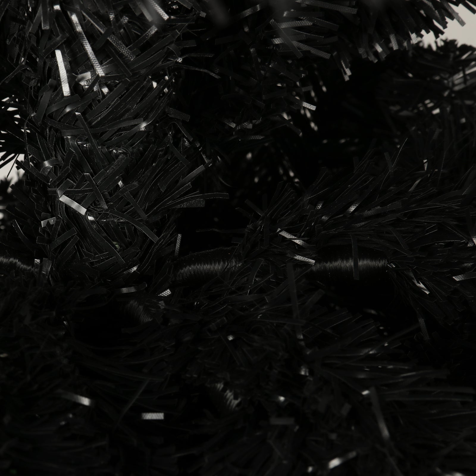 Closeup of dense black artificial Christmas tree branches with a slightly glossy finish