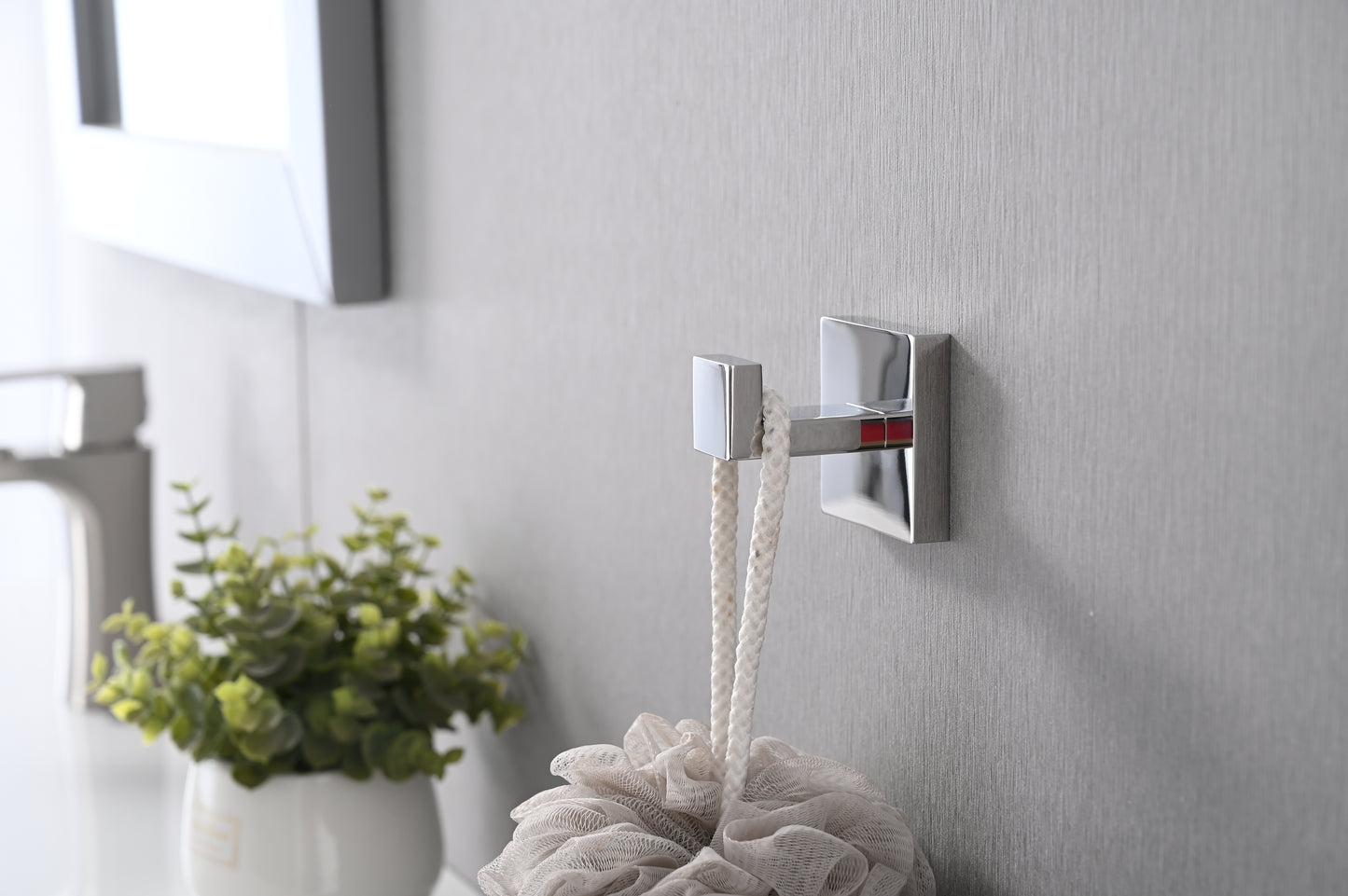 Modern square chrome bath hook holding a white rope loop complementing minimalist bathroom decor