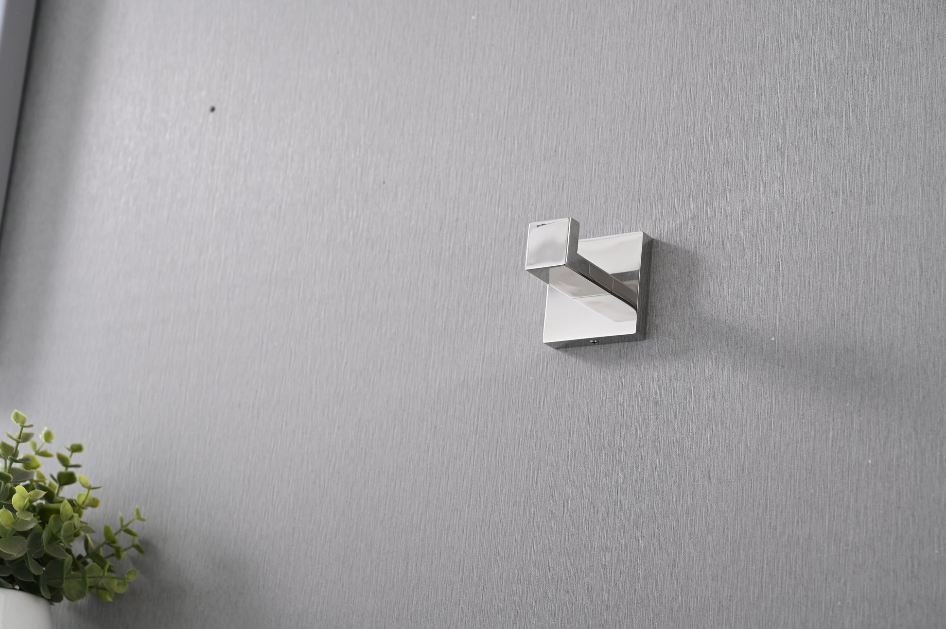 Polished chrome square robe hook mounted on textured grey wall