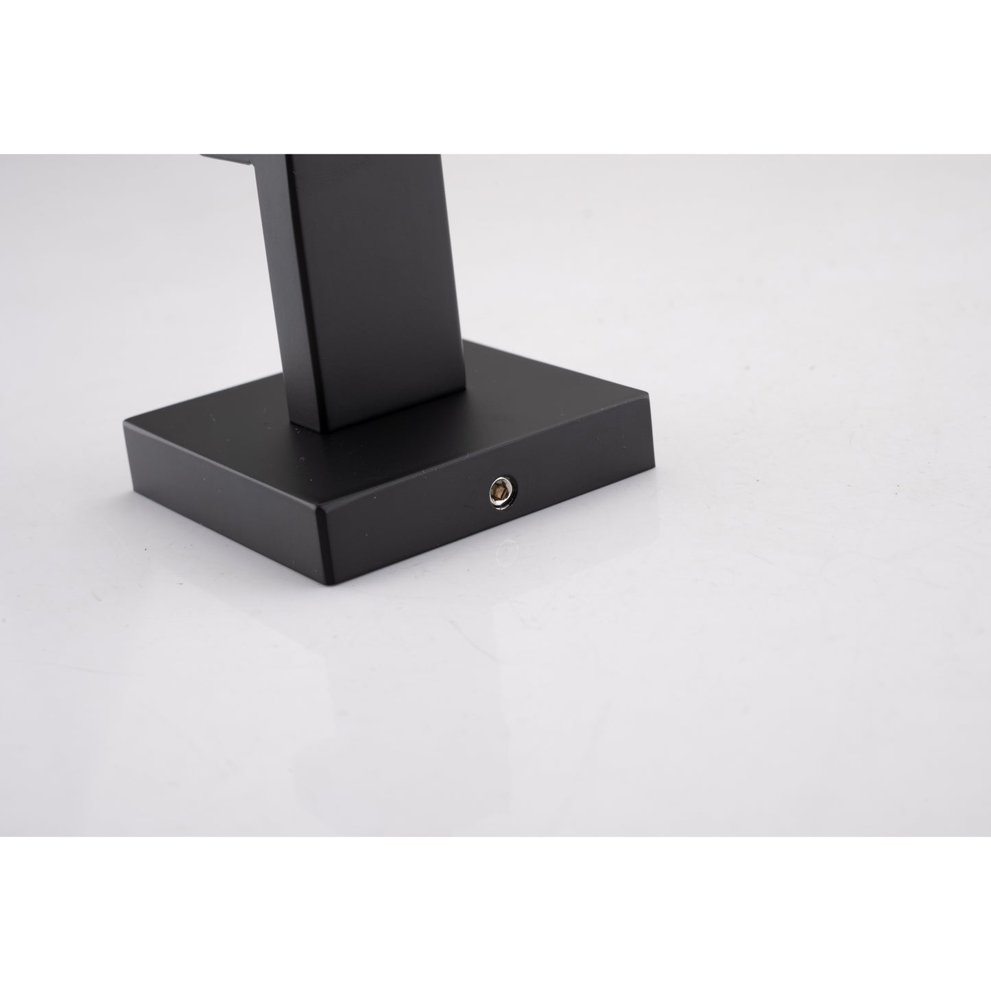 Closeup of a black metal lamp base with a mounting screw visible