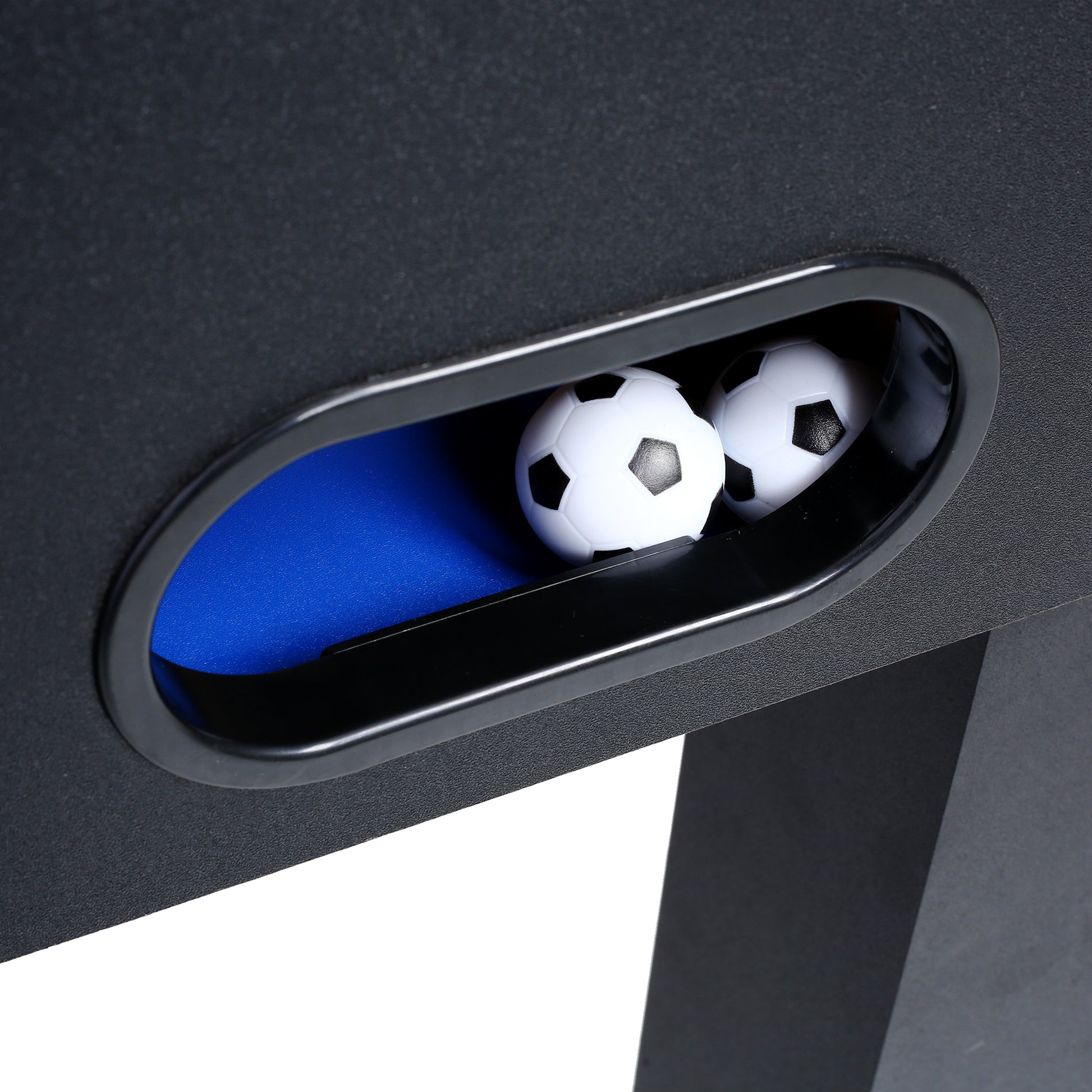 Closeup of two miniature foosball balls in a black plastic cup on a foosball table