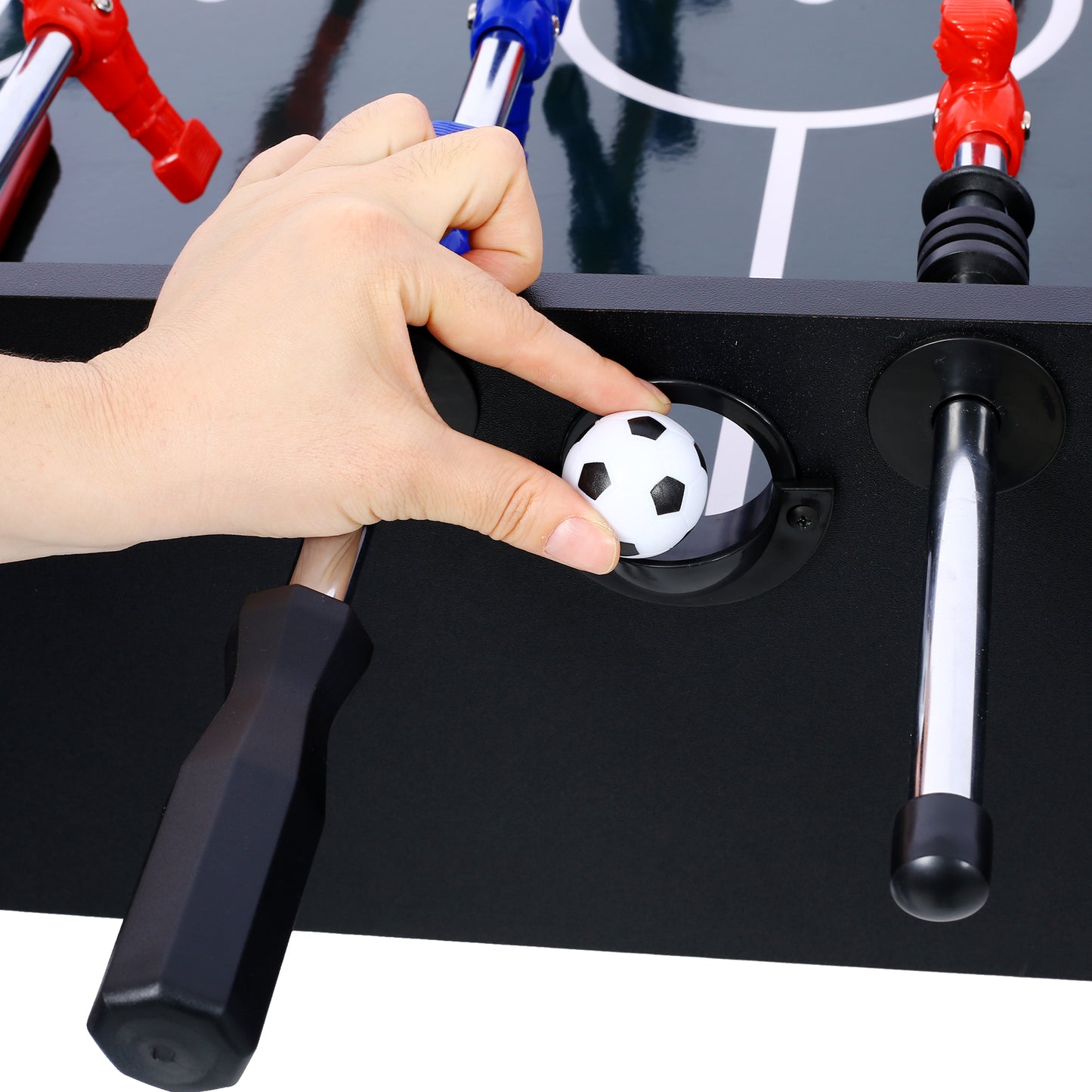 Close up of a hand placing a miniature soccer ball on a foosball table