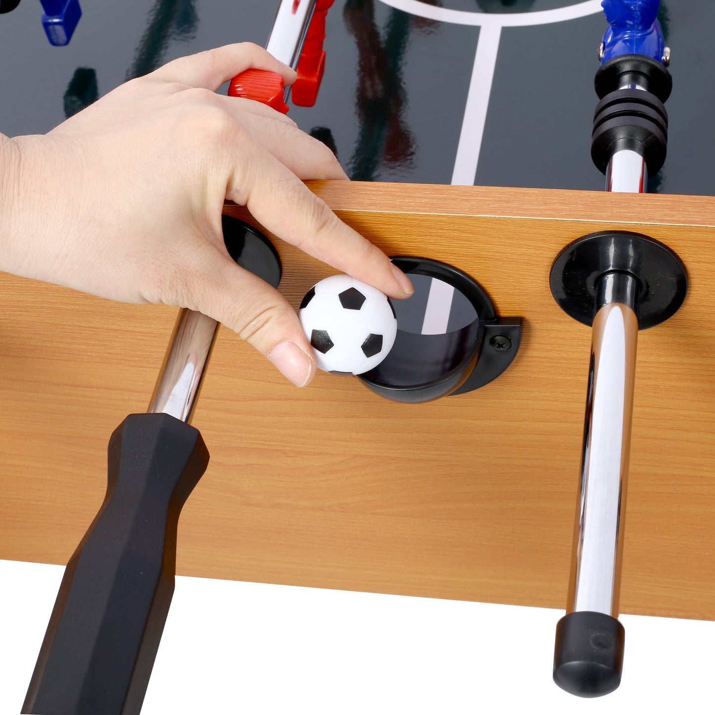 Hand places mini soccer ball into foosball table goal