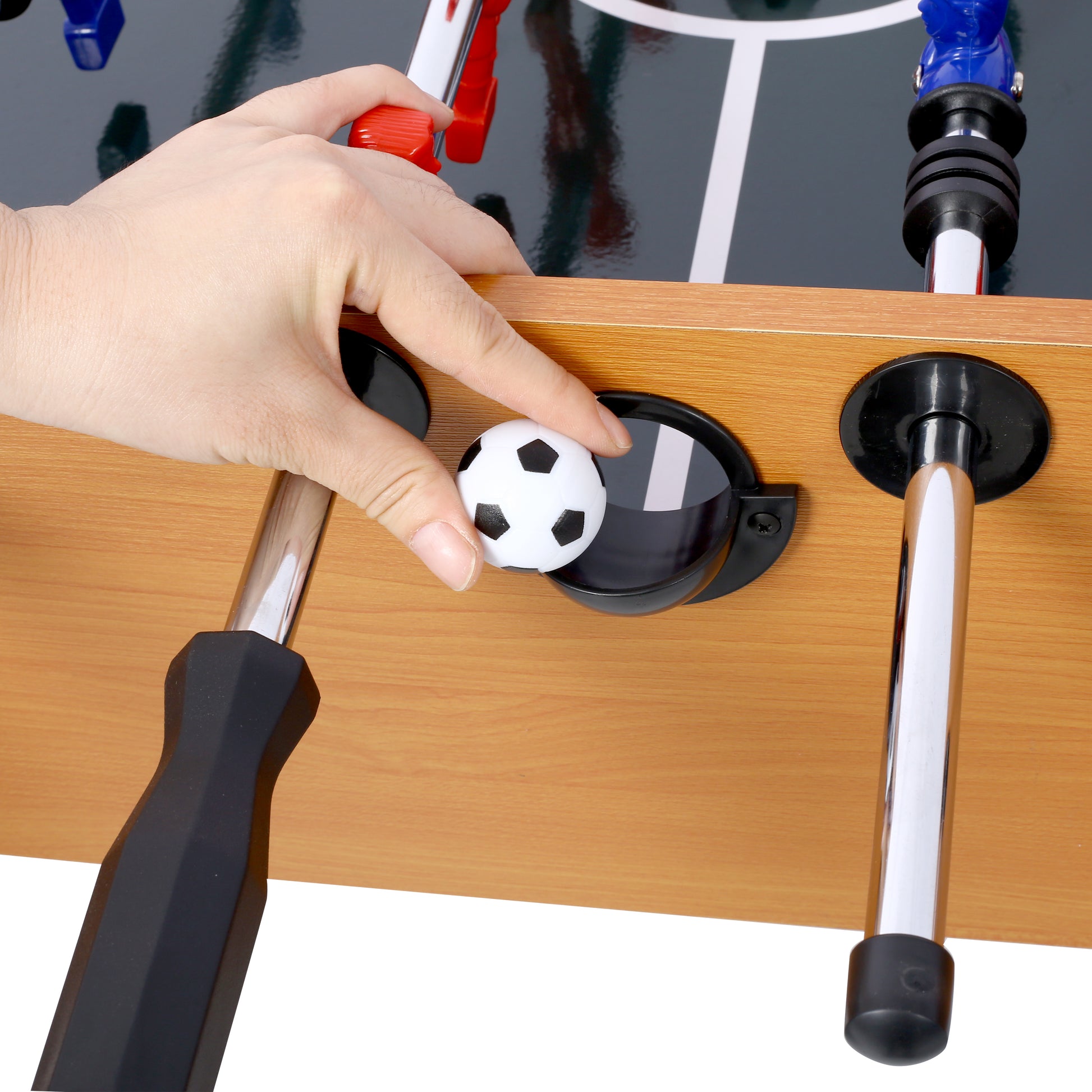 Hand places mini soccer ball into foosball table goal
