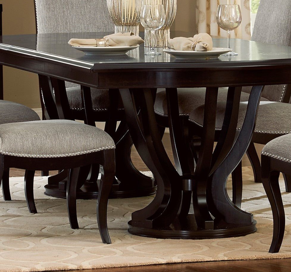 Dark wood dining table with intricate carved pedestal base and upholstered chairs