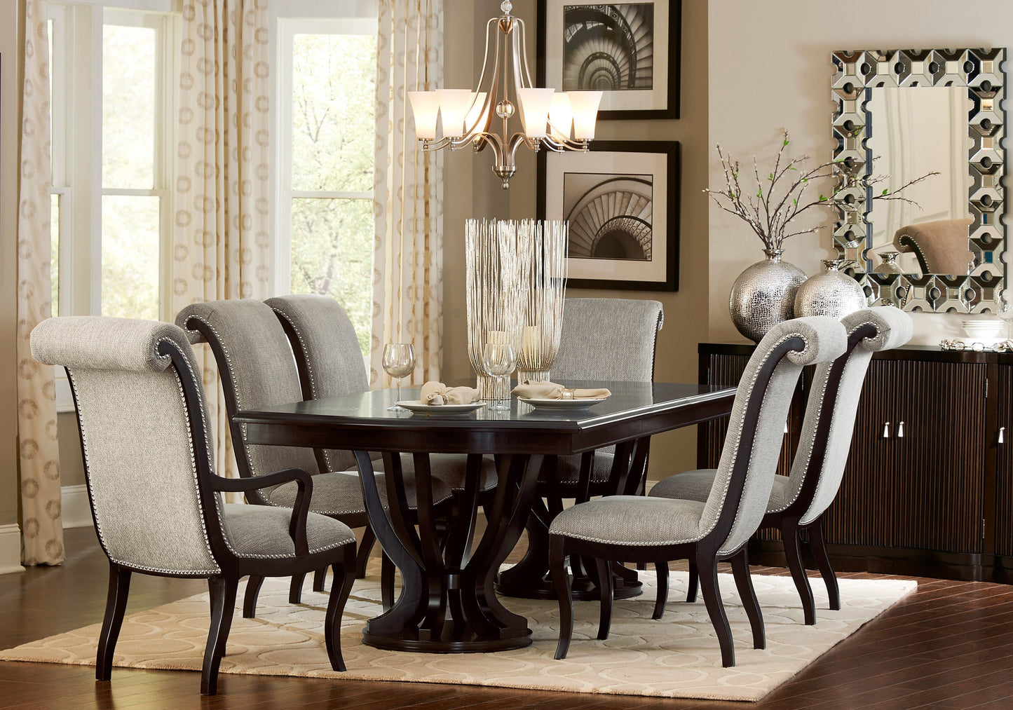 Elegant dark wood dining table with grey upholstered chairs and silver nailhead trim