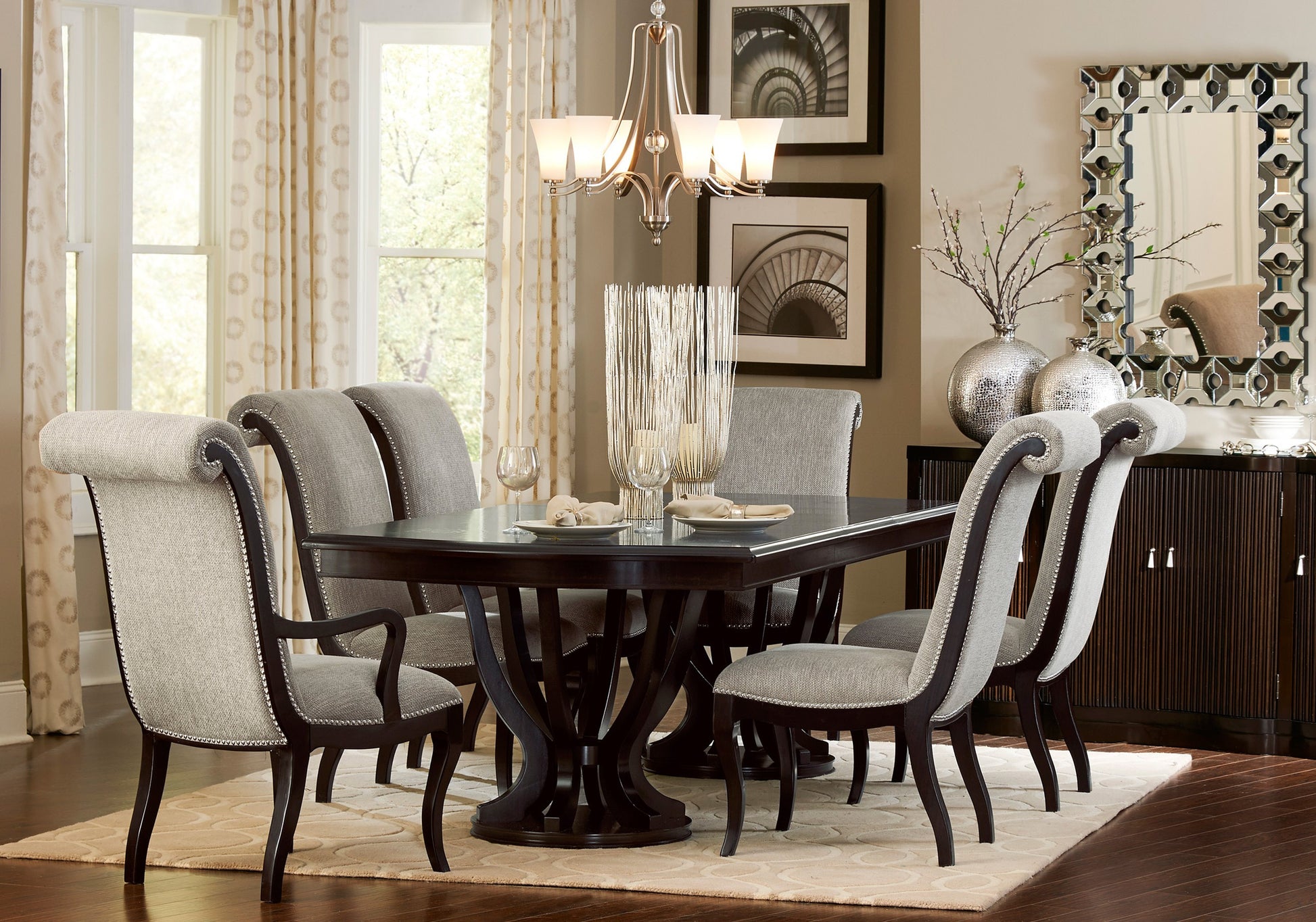 Elegant dark wood dining table with grey upholstered chairs and silver nailhead trim