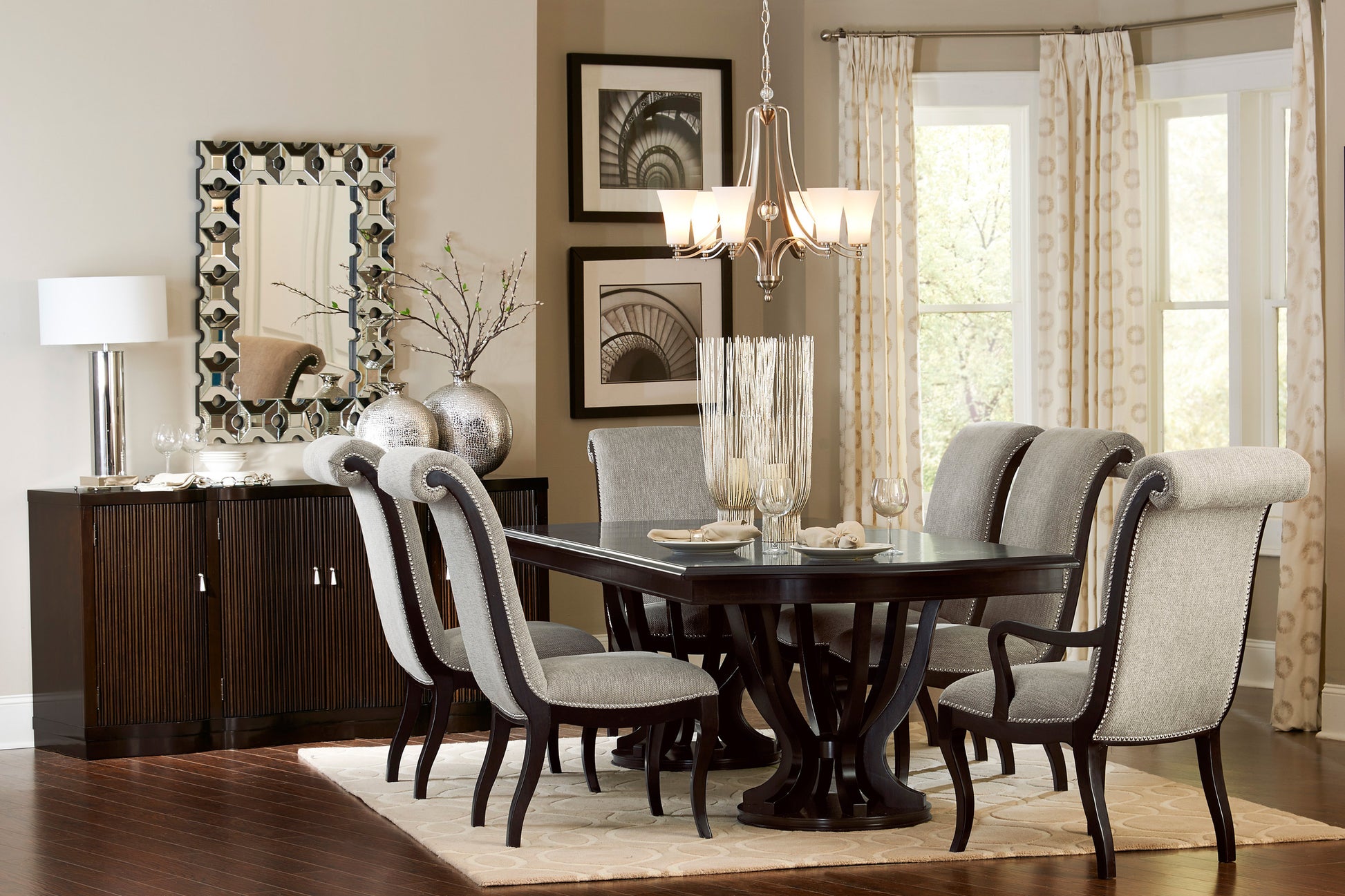 Dark wood pedestal dining table with six upholstered grey chairs with silver nailhead trim