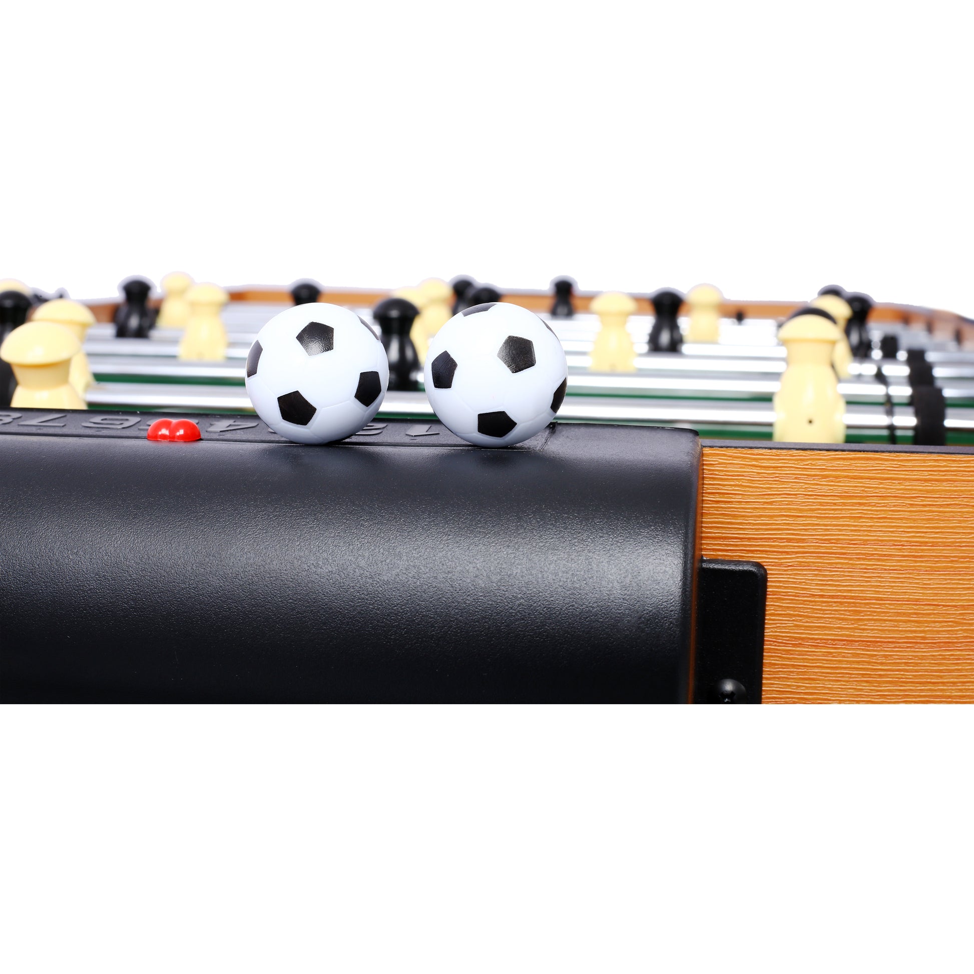 Closeup of two white and black mini soccer balls on a tabletop foosball game