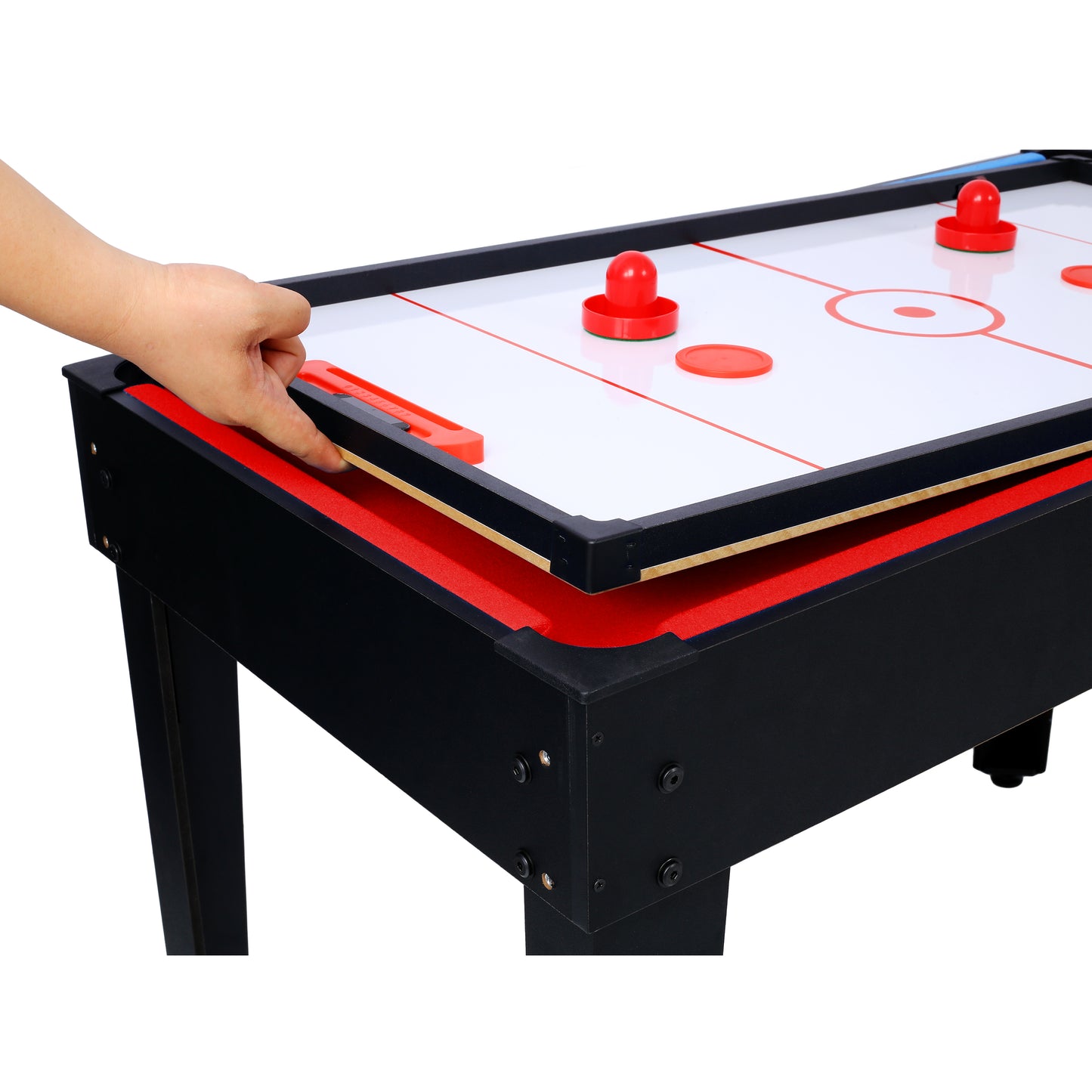 Compact tabletop air hockey table with red pucks and a hand adjusting the score keeper