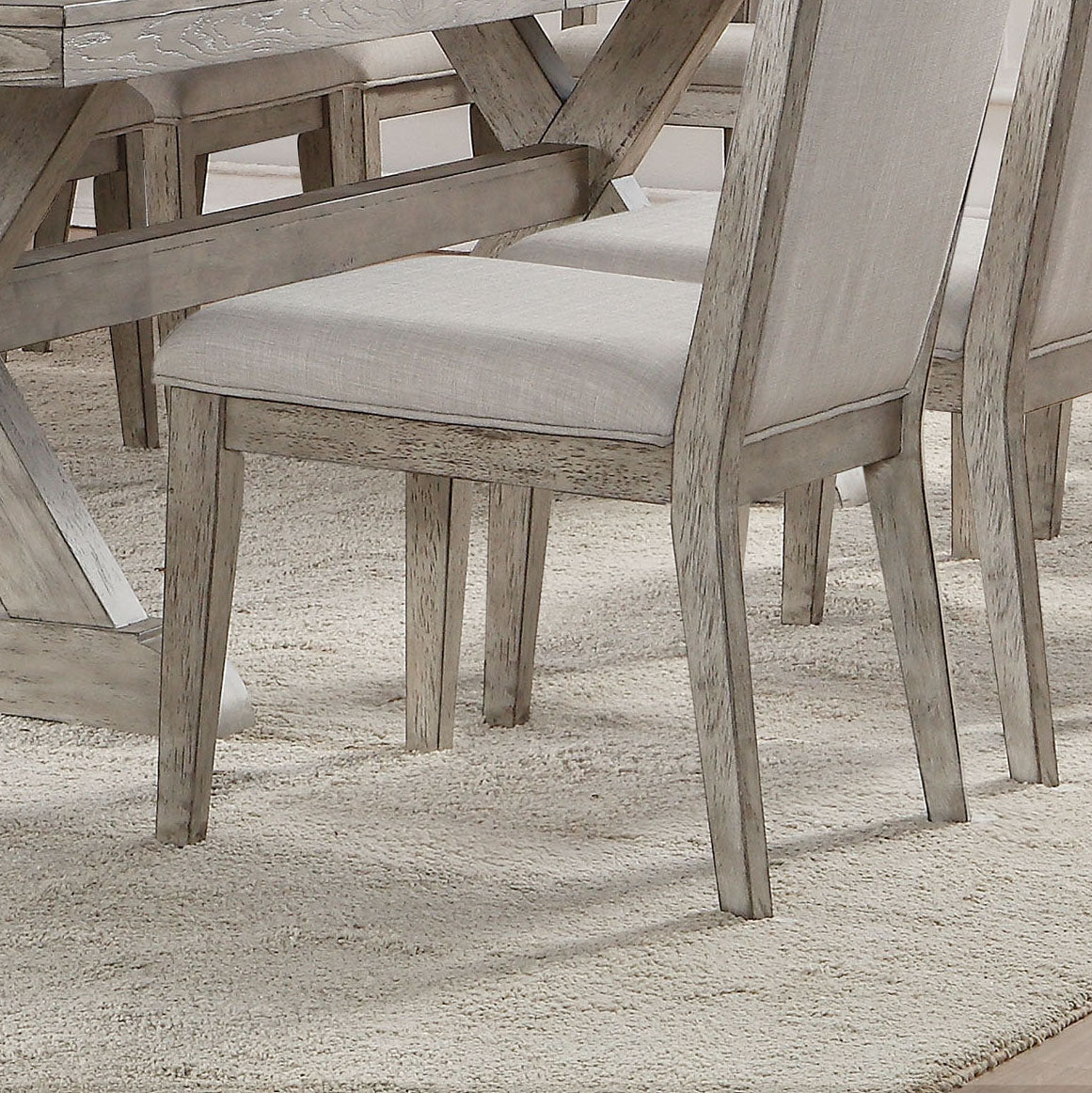 Closeup of distressed grey wood dining chairs with beige linen seats on a shag rug