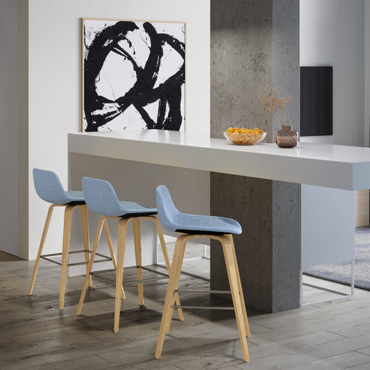 Three light blue fabric bar stools with natural wood legs and silver footrests in a modern kitchen
