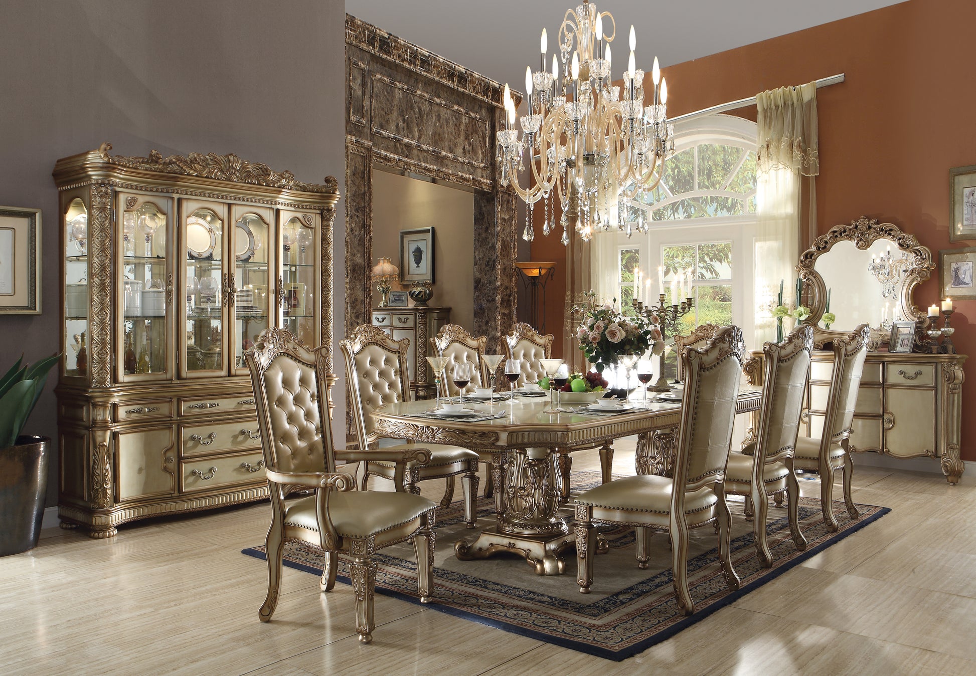 Ornate gold dining table set with tufted cream leather chairs and crystal chandelier