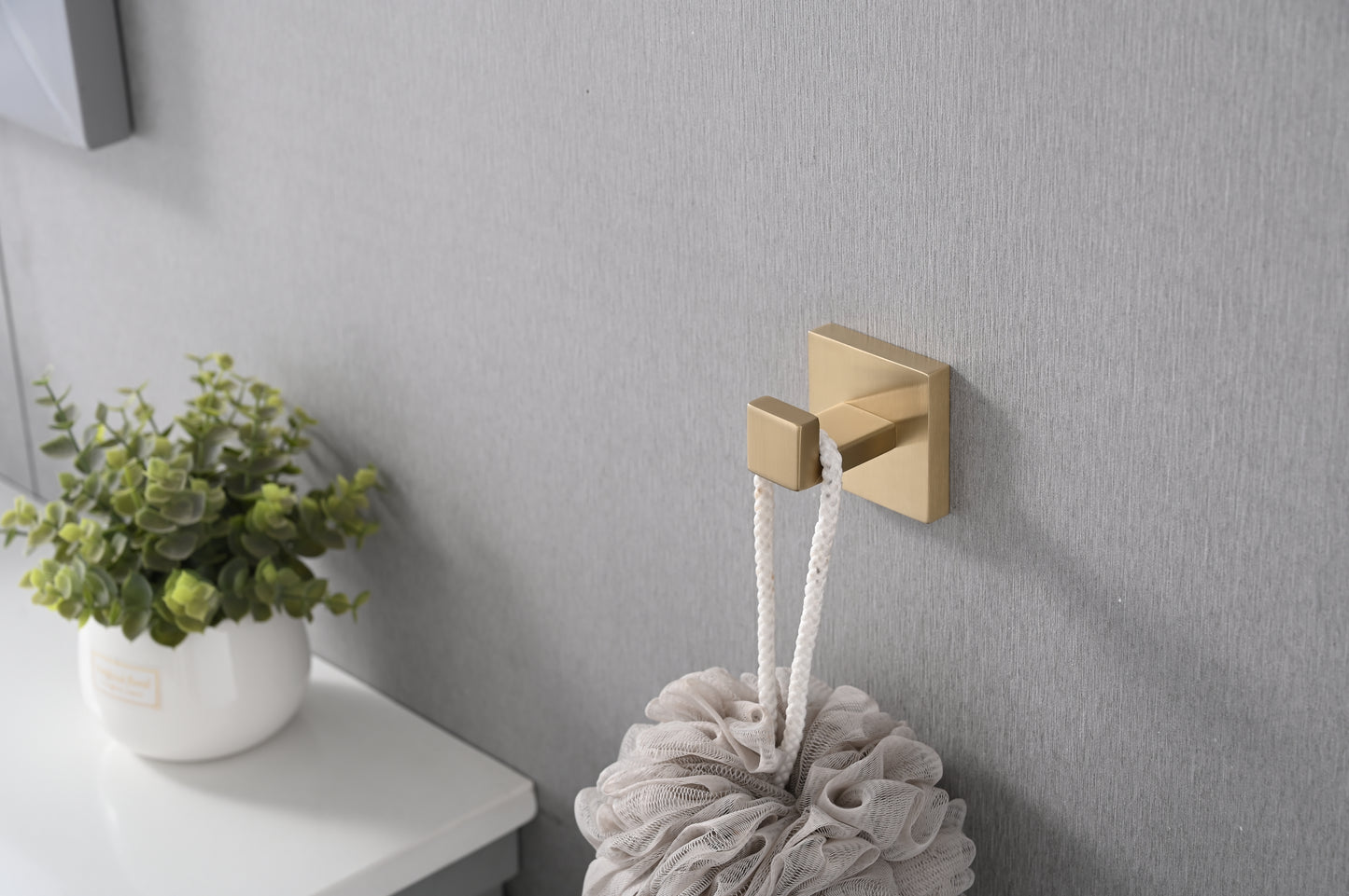 Modern brass bathroom hook holding a textured loofah