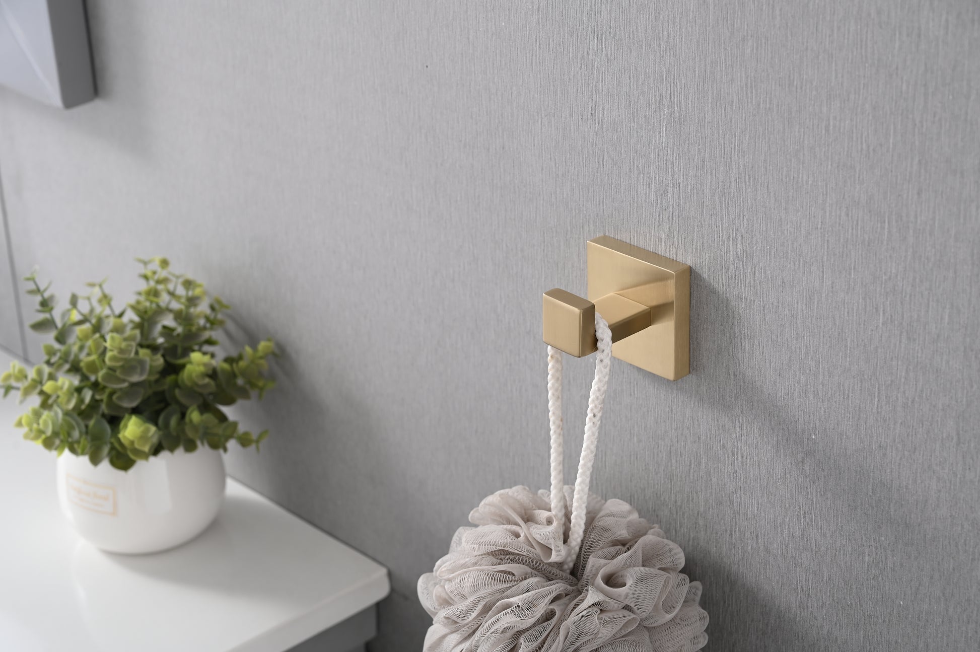 Modern brass bathroom hook holding a textured loofah