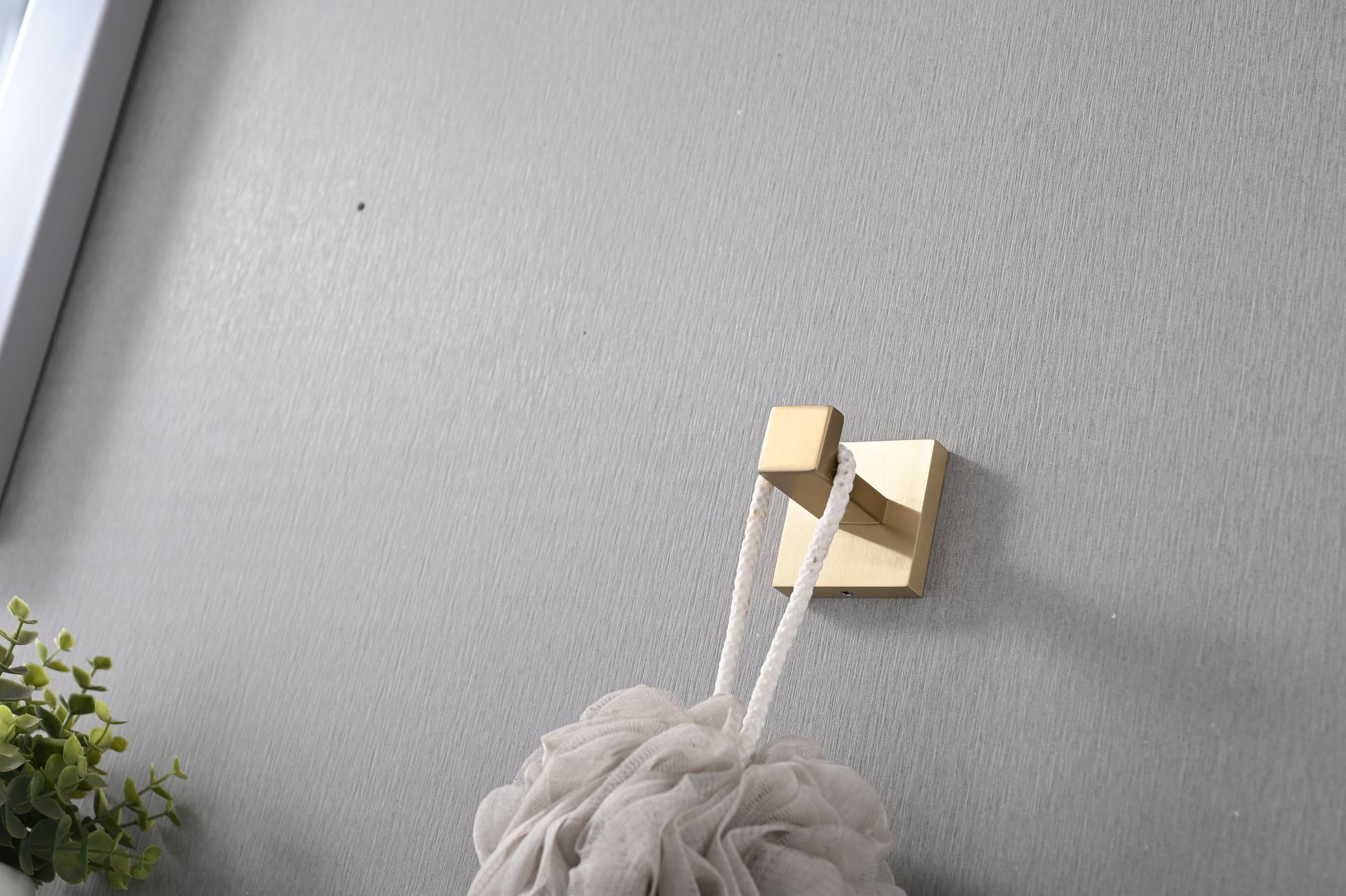 Gold square bath hook holding a white loofah sponge