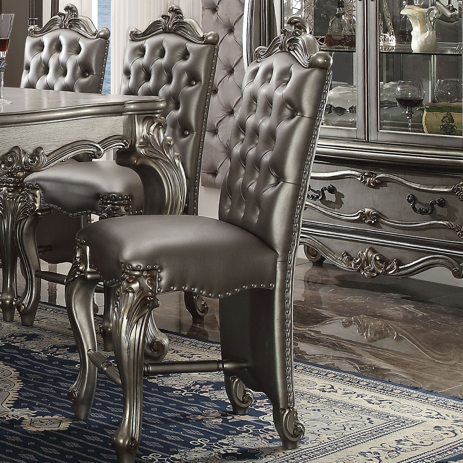 Tufted grey leather dining chair with ornate silver carved legs and nailhead trim