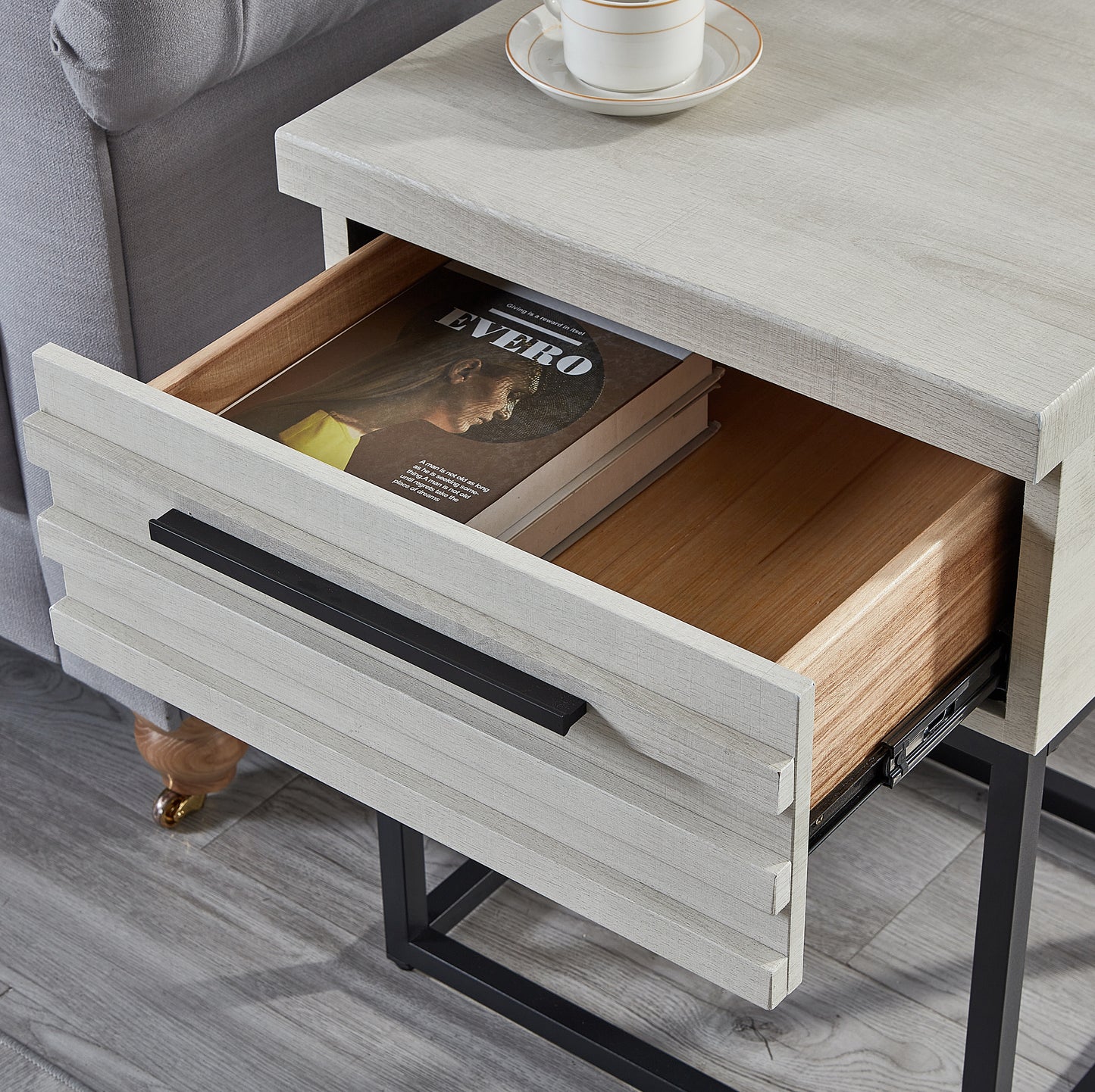 Distressed grey wood side table with one open drawer revealing a book and a black handle