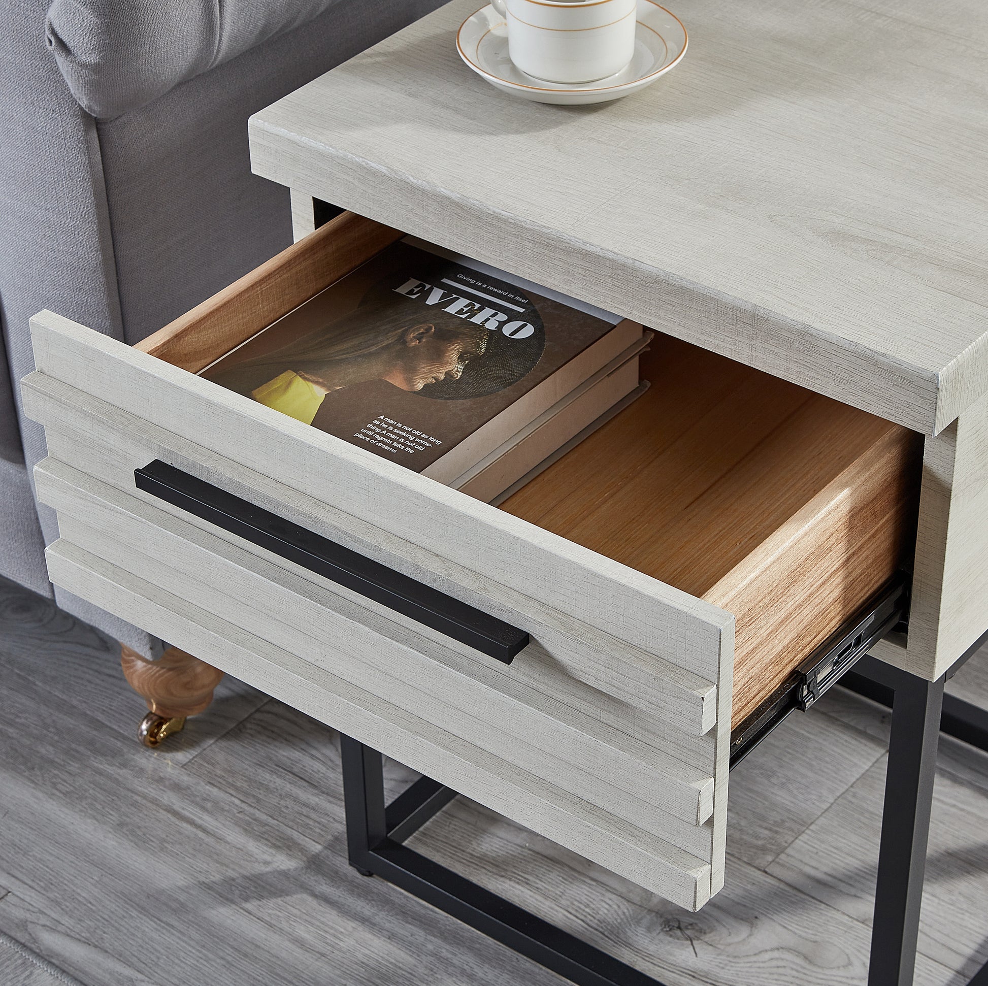 Distressed grey wood side table with one open drawer revealing a book and a black handle
