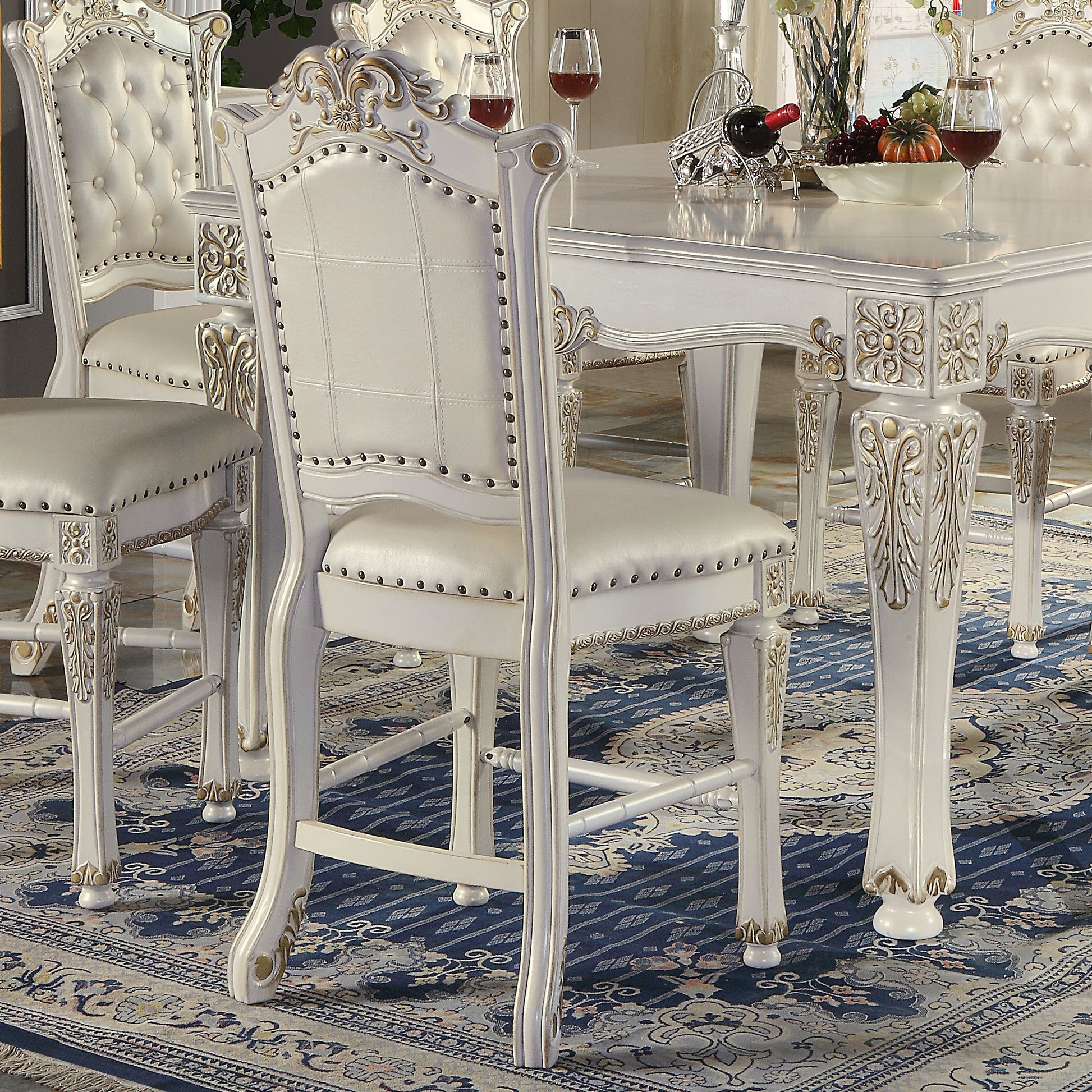 White tufted upholstered dining chair with ornate carved legs and brass tacks