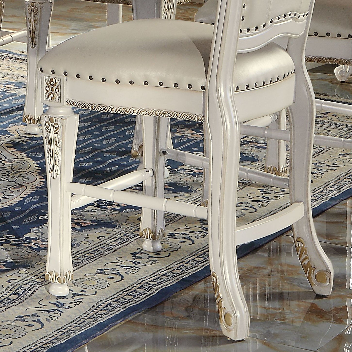 White upholstered bar stool with ornate gold accents and nailhead trim