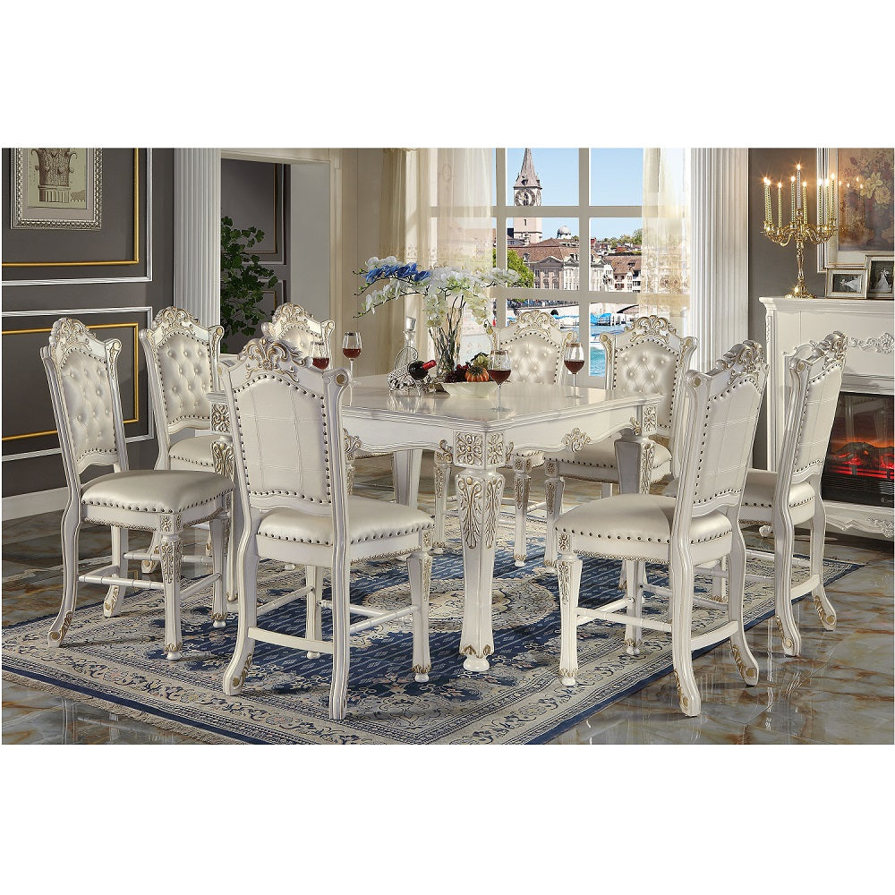 White tufted leather dining chairs with ornate carving around a matching table