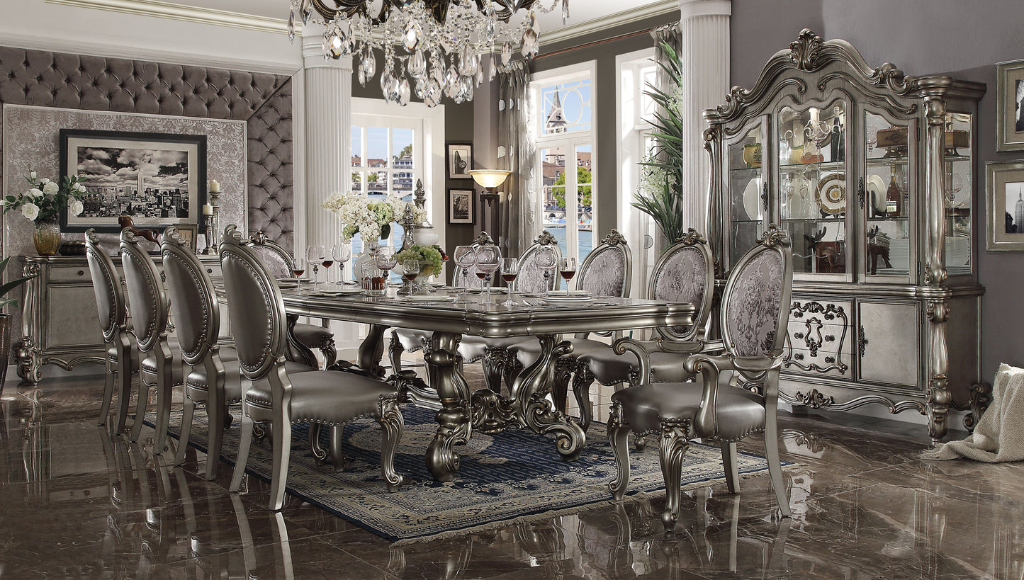 Ornate silver dining table with upholstered chairs and crystal chandelier
