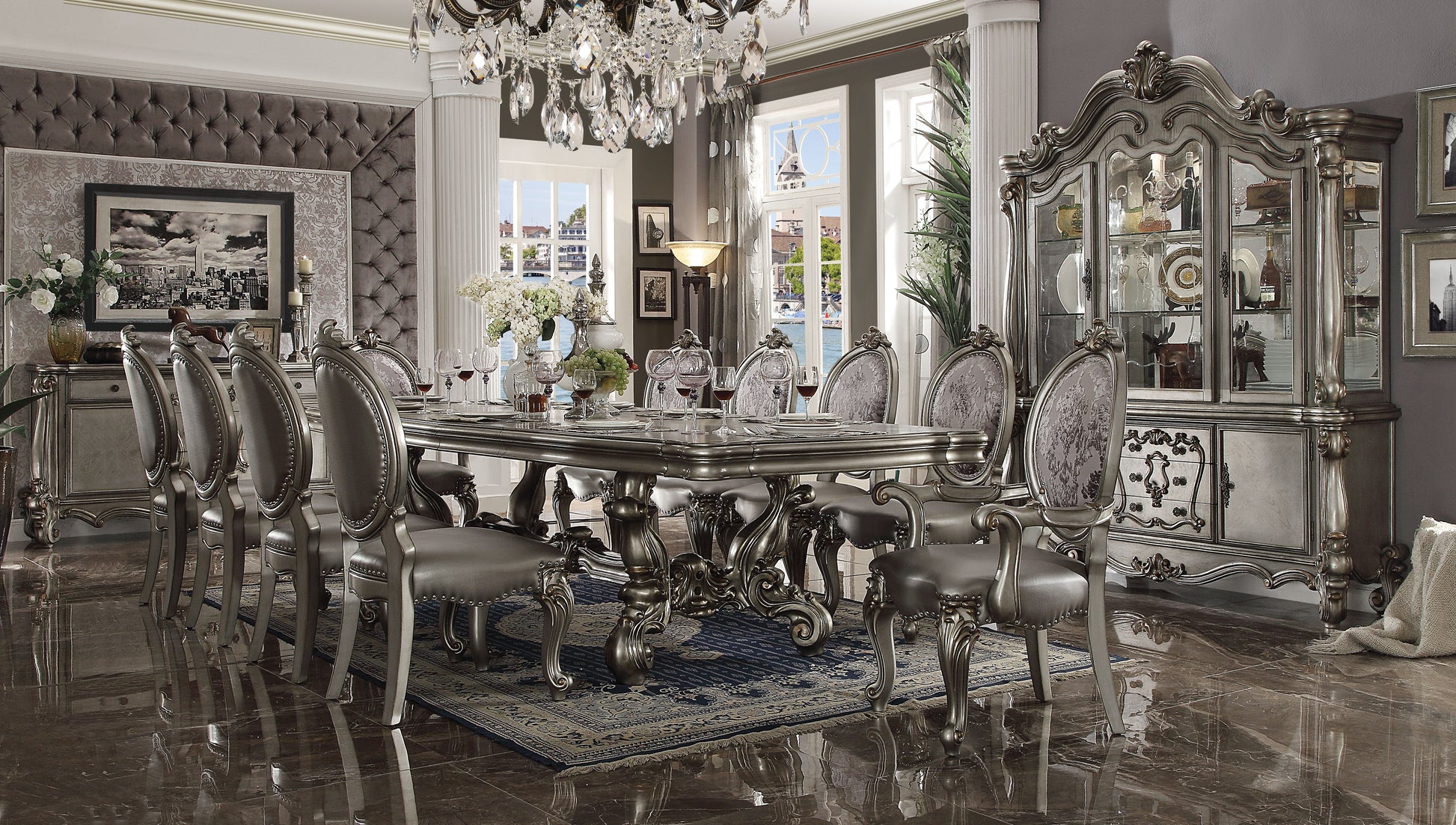Ornate silver dining table with upholstered chairs and crystal chandelier