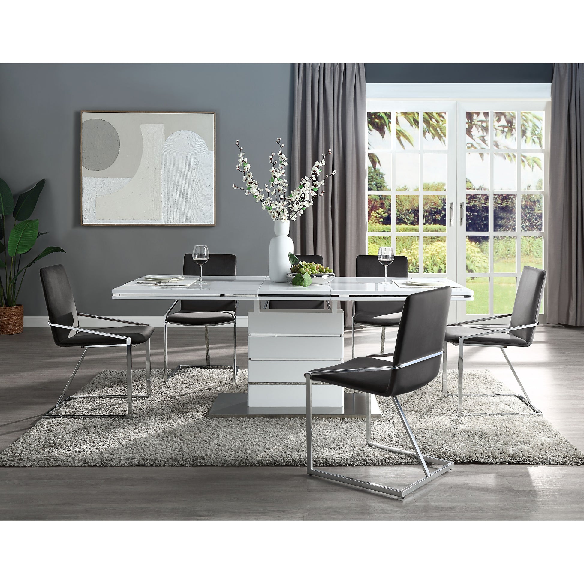 Modern white pedestal dining table with chromelegged dark grey chairs