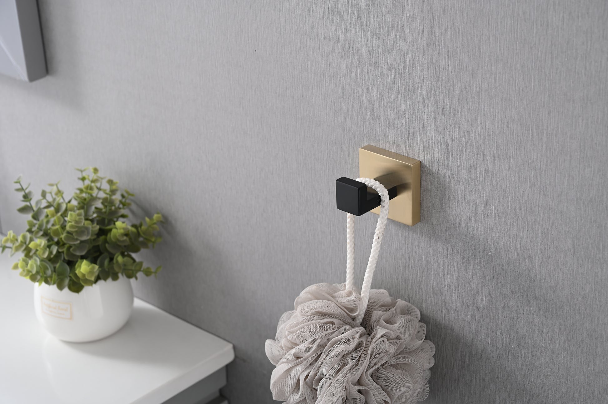 Modern gold and black bath hook holding a textured shower pouf