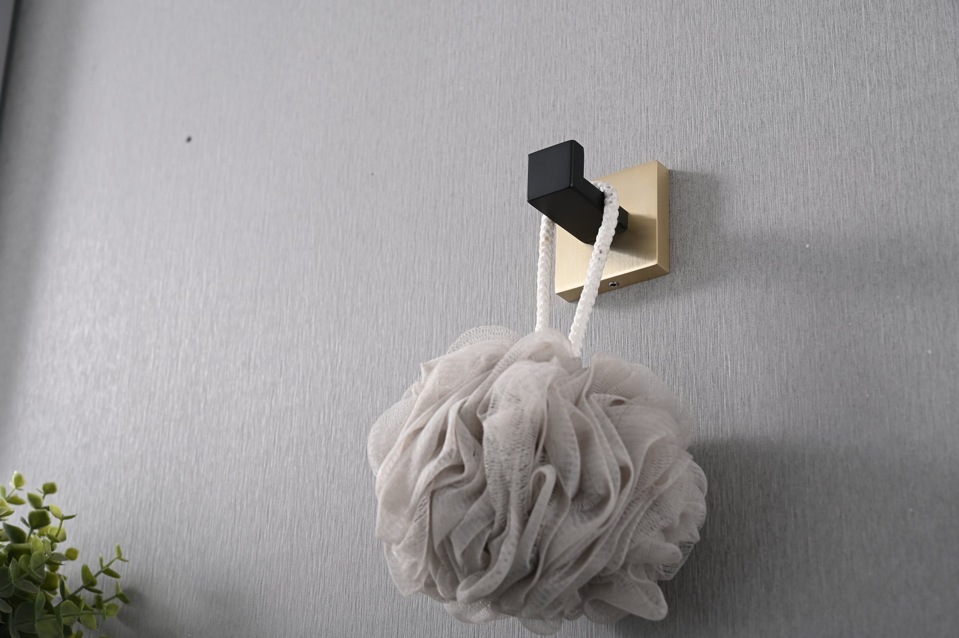 Brushed gold and black modern bath hook holding a soft beige loofah