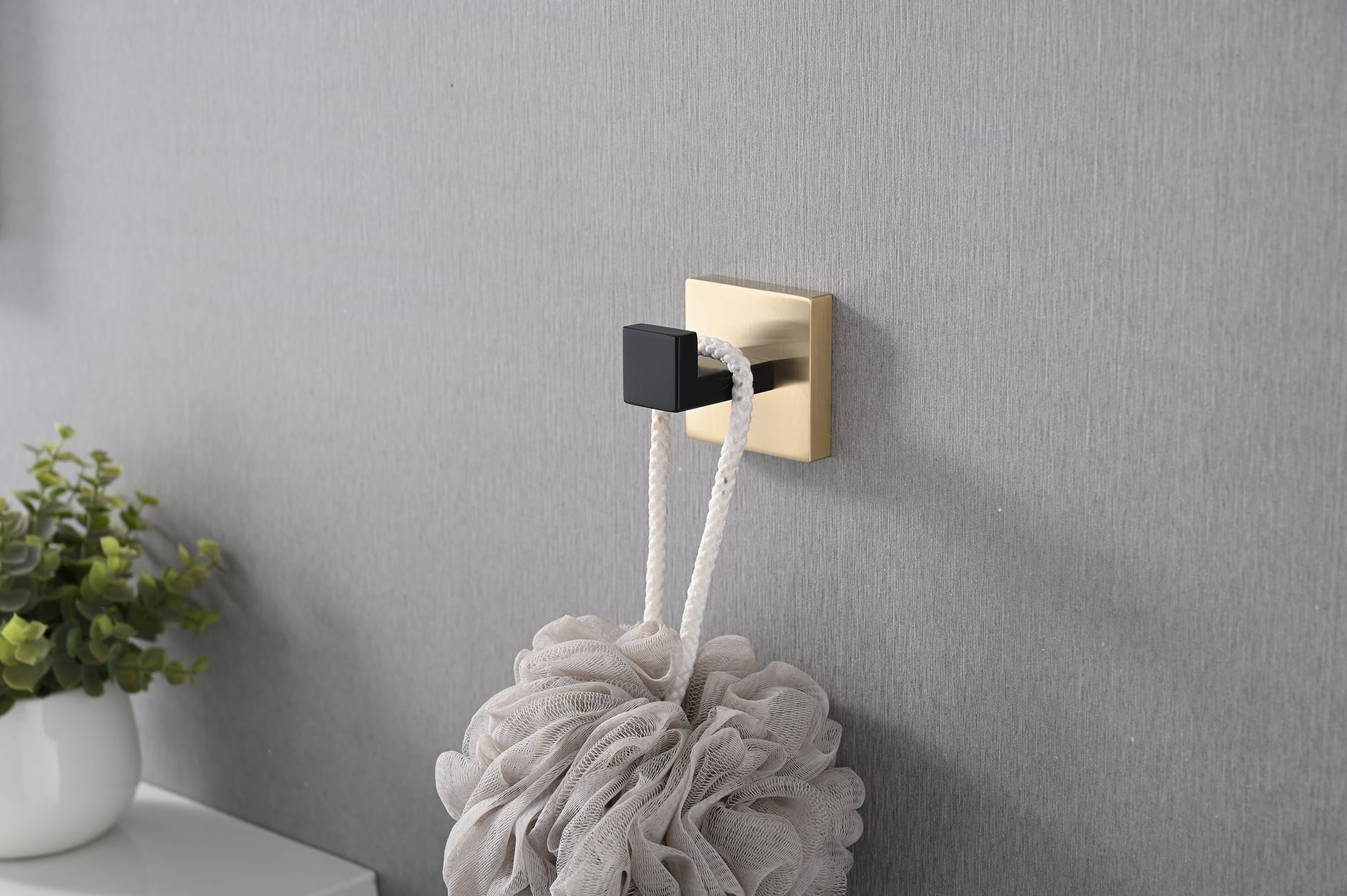 Gold and black modern bathroom hook holding a beige loofah