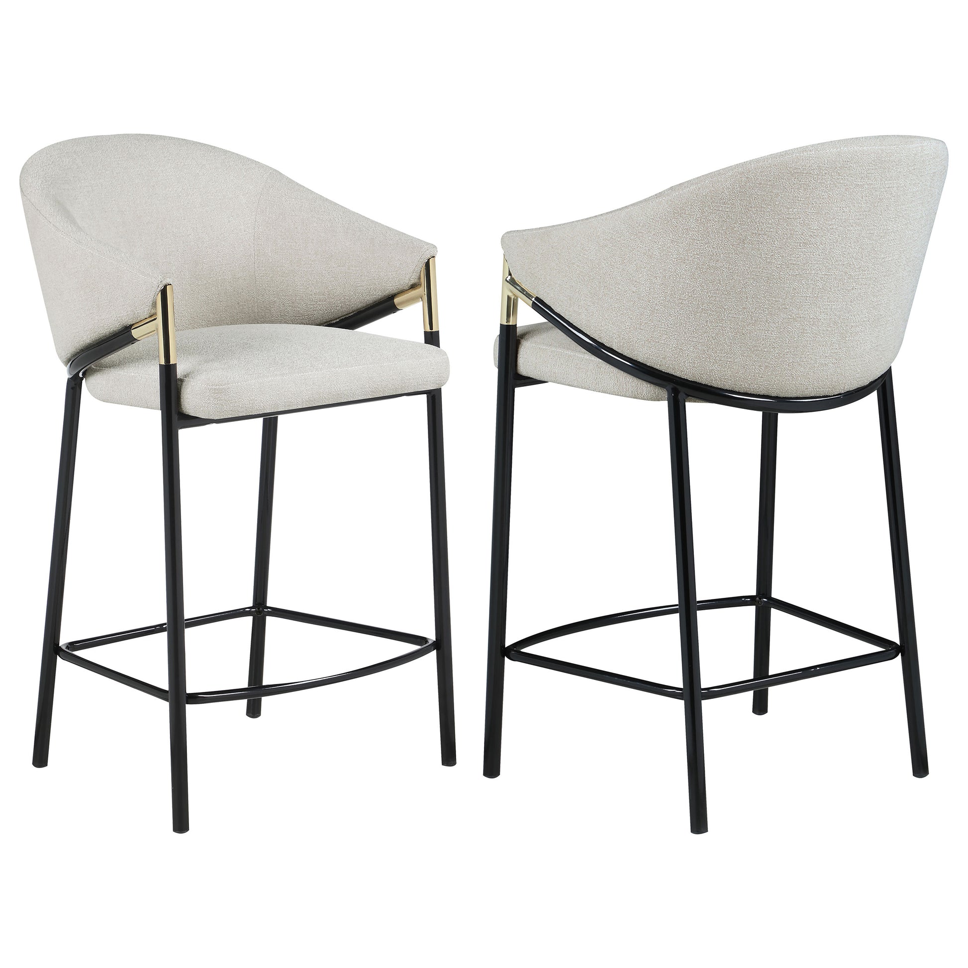 Two upholstered bar stools in a light neutral tone with black metal legs and gold accents