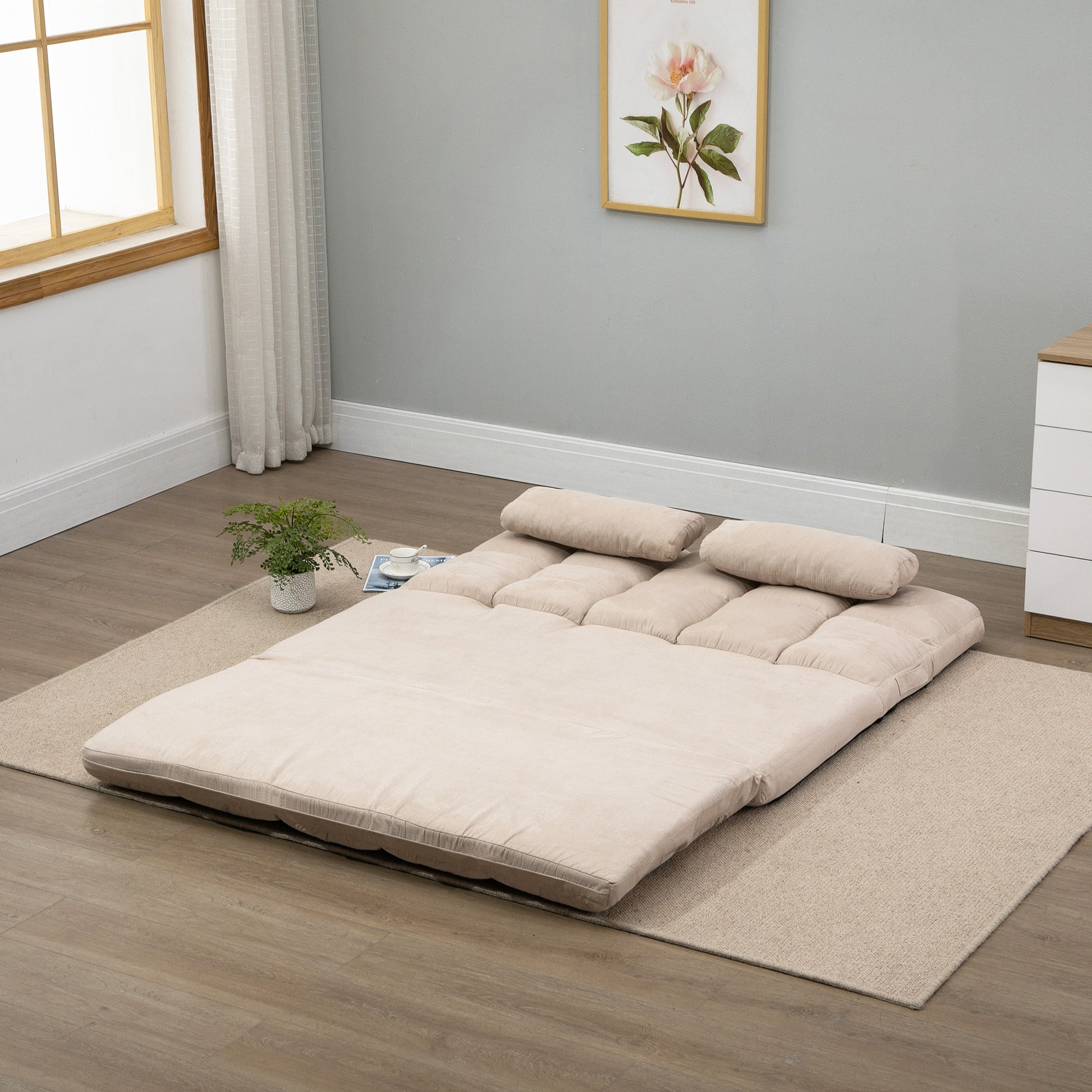 Beige convertible sofa bed laid flat on a rug featuring plush cushioning and two lumbar pillows