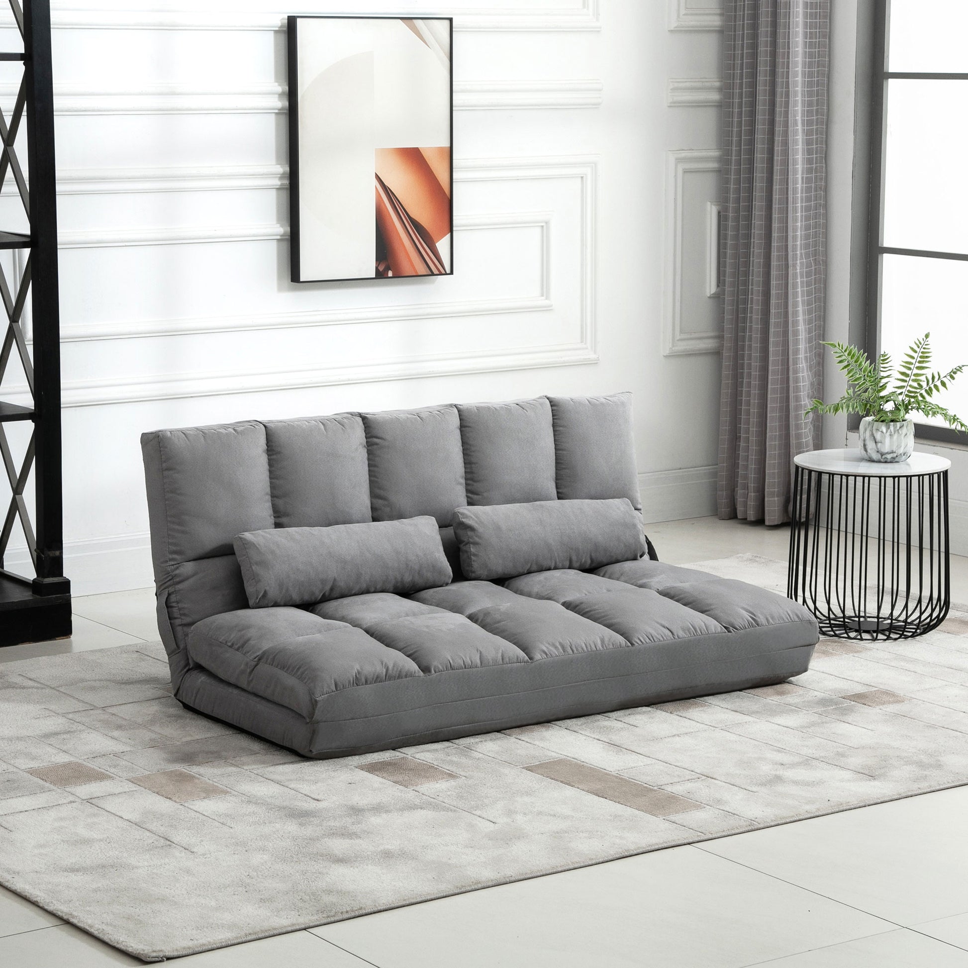Gray upholstered convertible sofa bed with tufted cushions and matching throw pillows