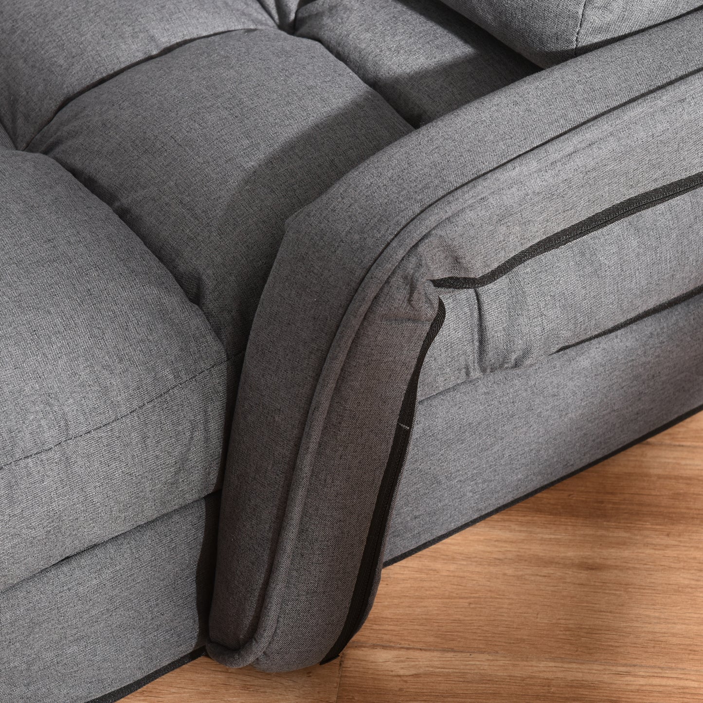 Closeup of a grey textured fabric sofa armrest with black piping detail