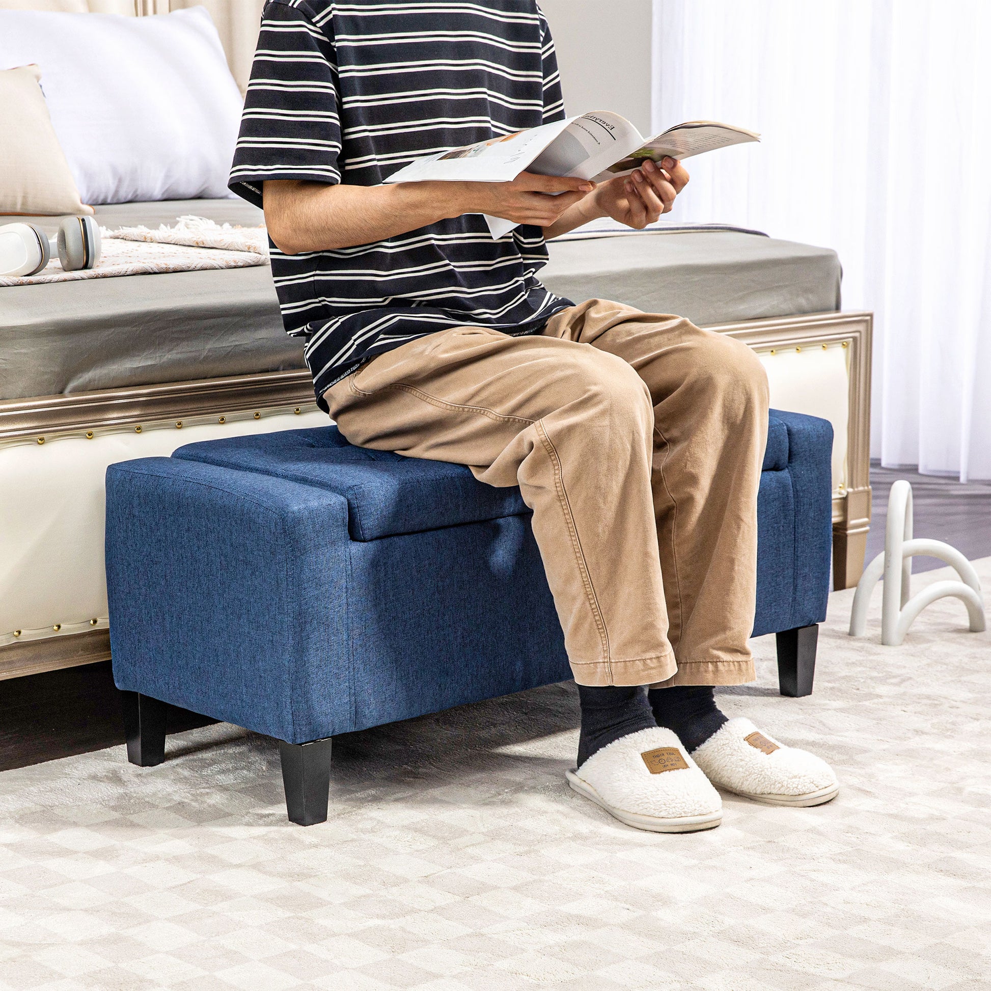 Deep blue upholstered storage ottoman with tufted lid and black legs