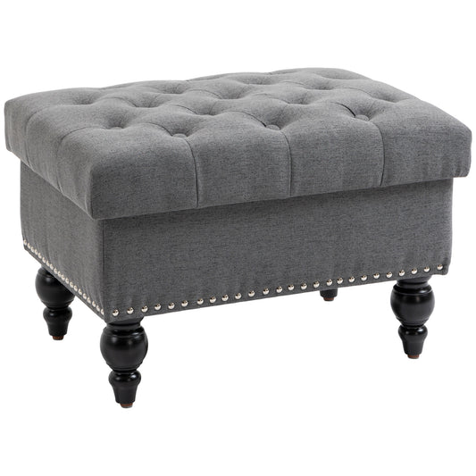 Grey tufted fabric storage ottoman with silver nailhead trim and dark wooden legs