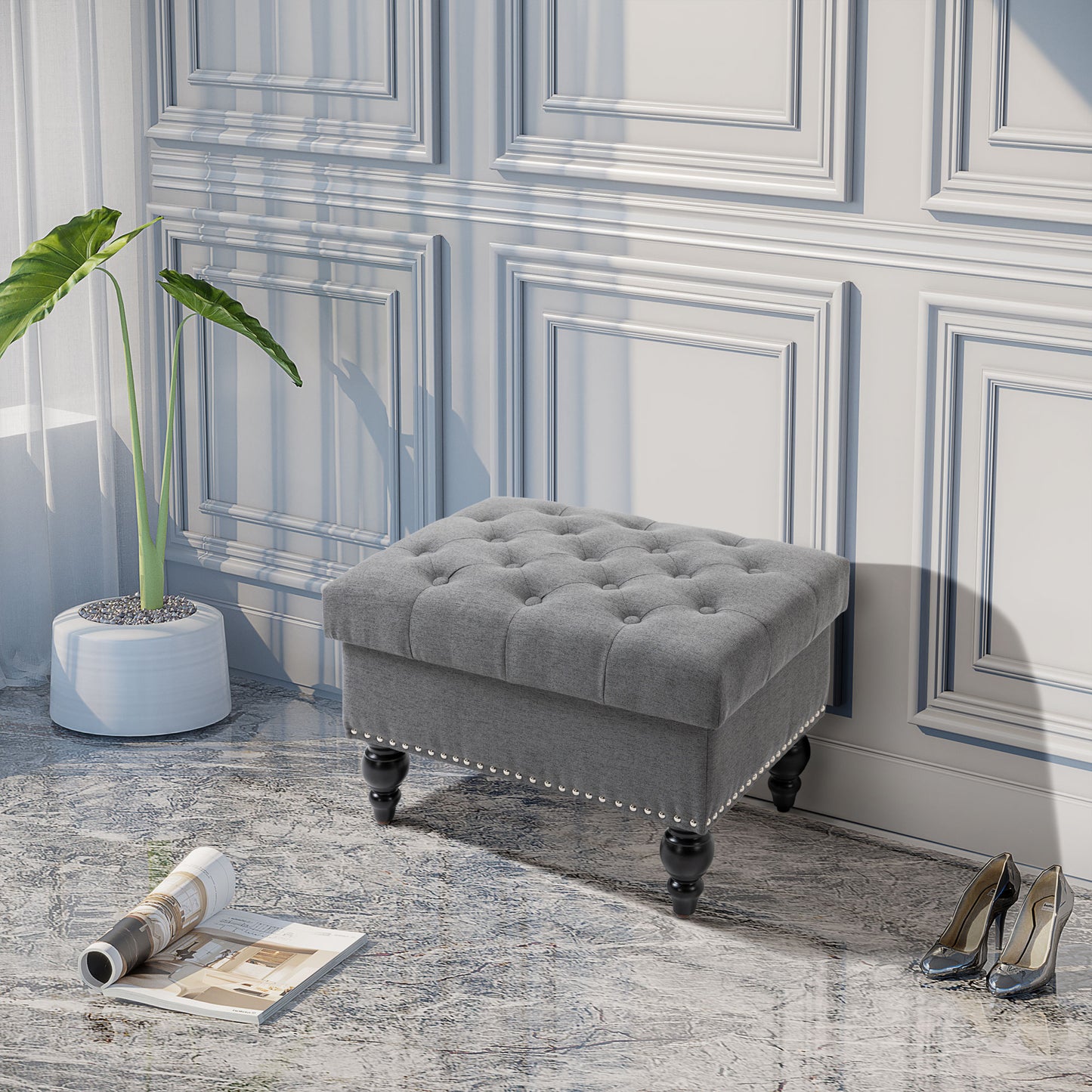 Grey tufted fabric ottoman with silver nailhead trim and black wooden legs