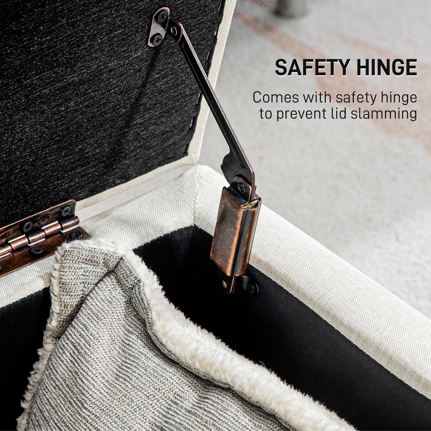Closeup of a black safety hinge attached to a beige upholstered ottoman for safe lid closure