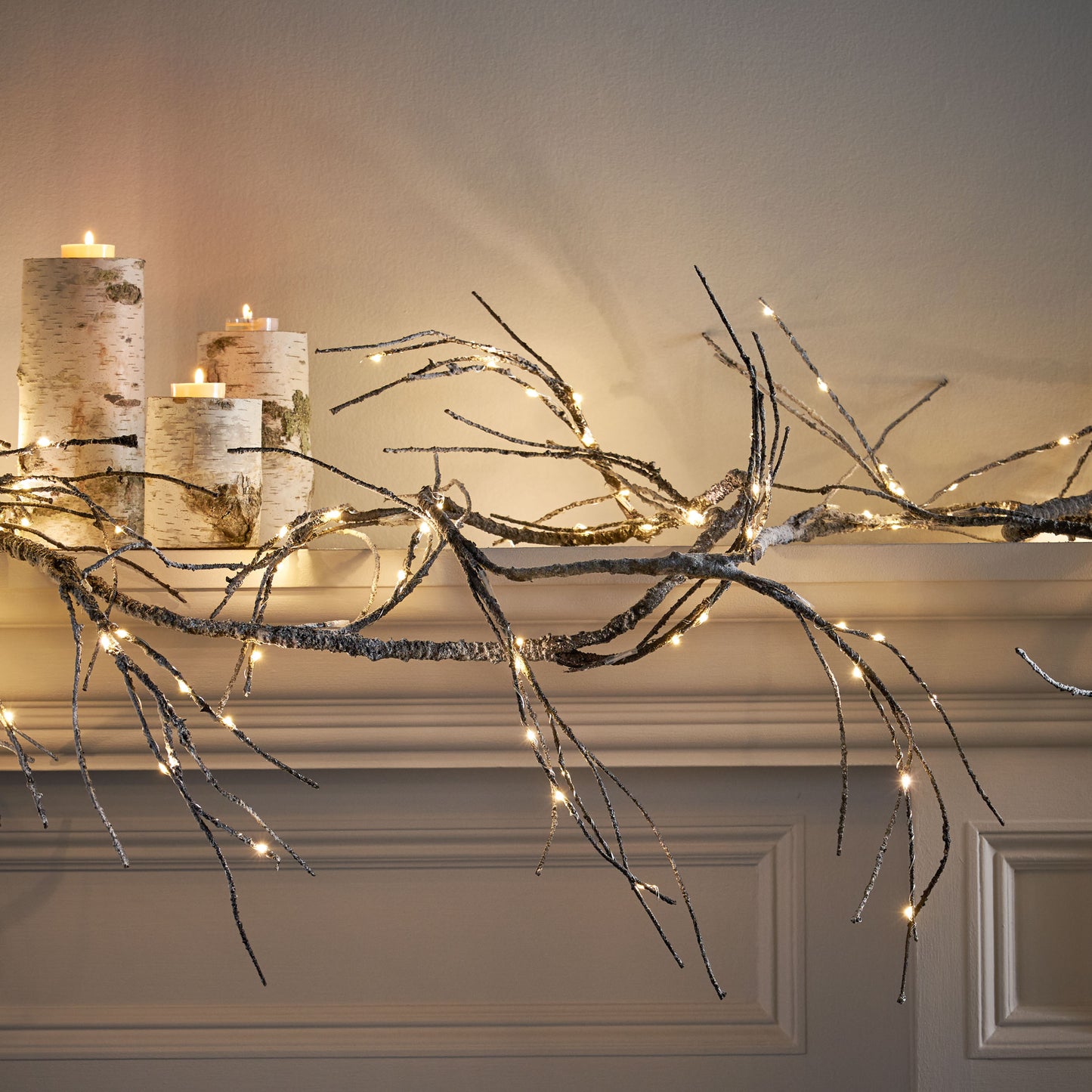 Birch log candle holders with flickering tea lights create a cozy winter ambiance