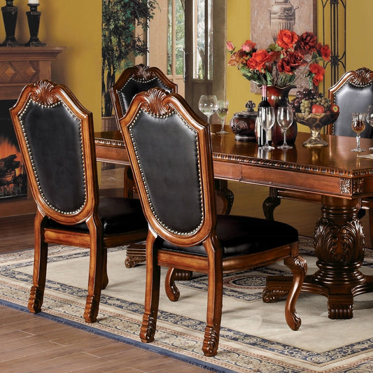 Ornate wood dining chairs with black leather upholstery and nailhead trim