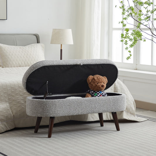 Oval storage ottoman with gray textured fabric and wooden legs open lid revealing teddy bear