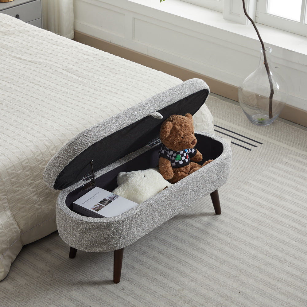 Grey fabric storage bench with wooden legs open to reveal teddy bears and book