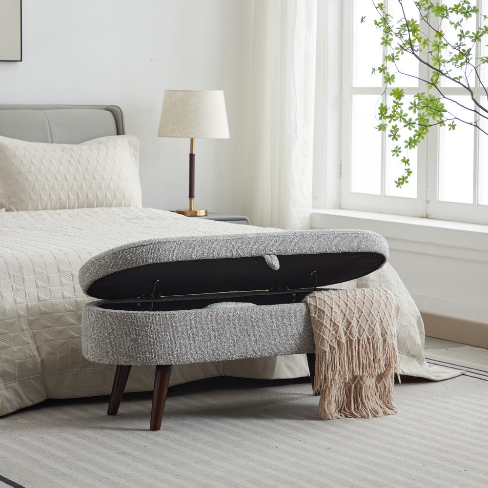 Gray textured storage ottoman with dark wood legs open showing storage