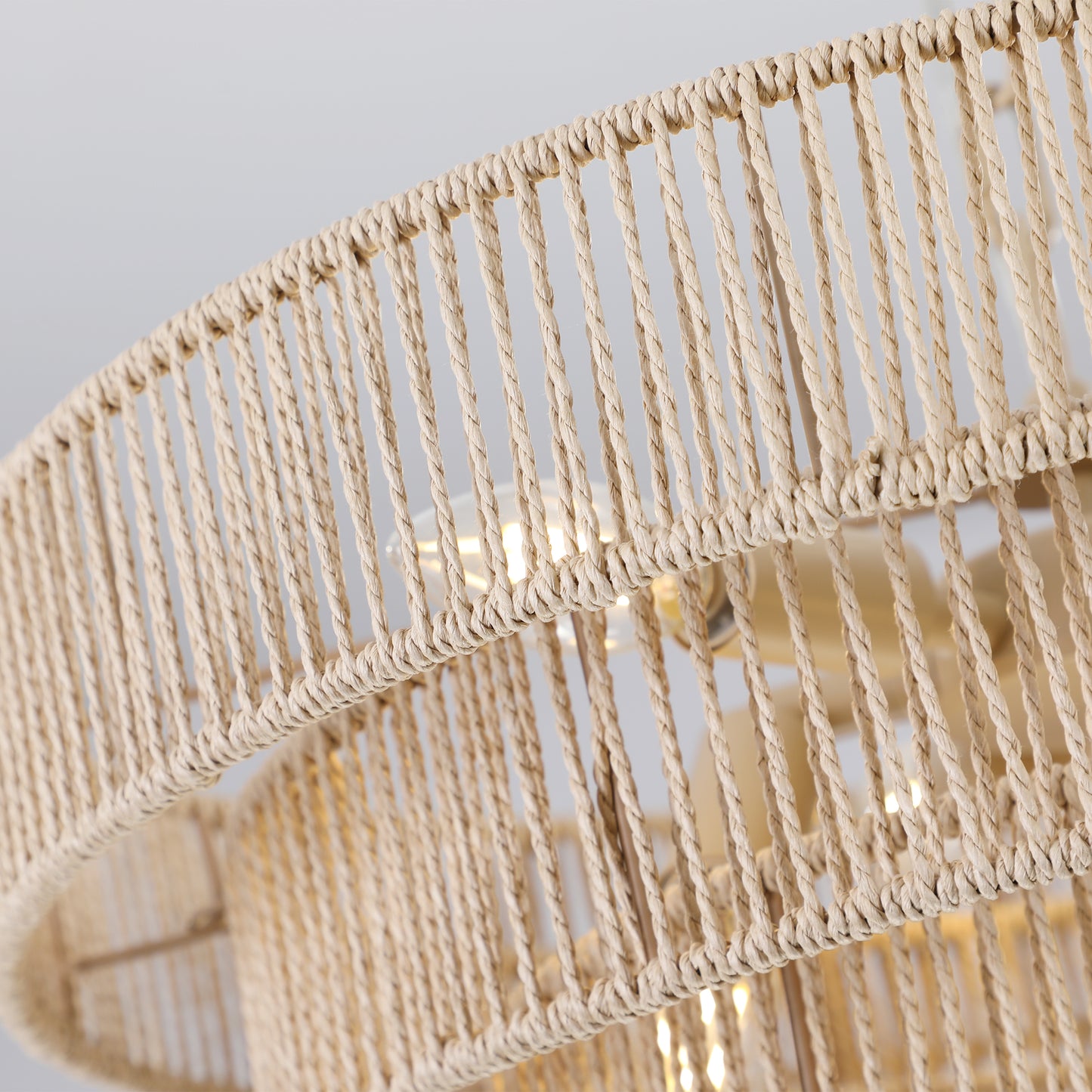 Closeup of a beige woven rope pendant light with visible bulbs accentuating its natural texture
