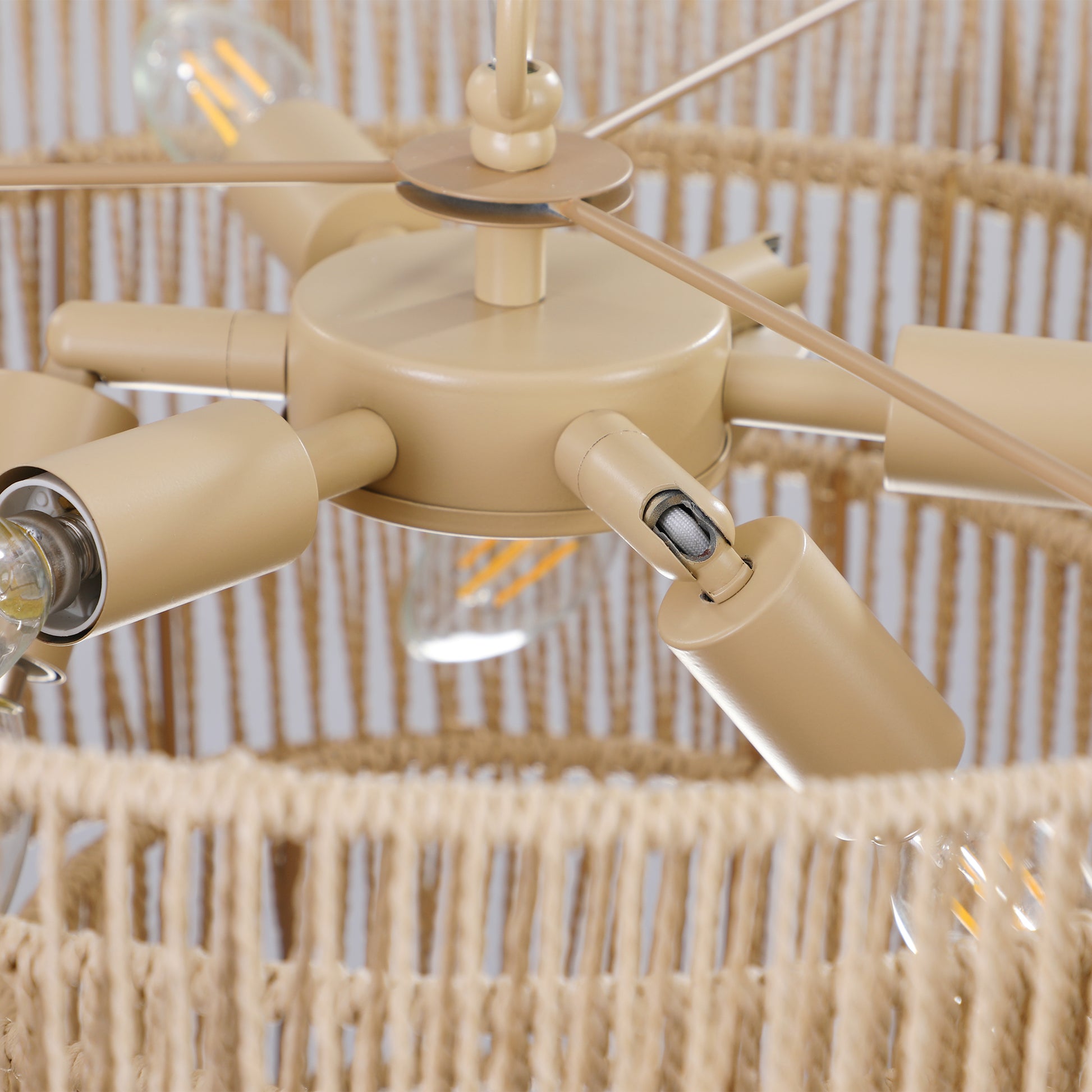 Closeup of a beige metal chandelier base with visible light bulb sockets and a woven rope shade